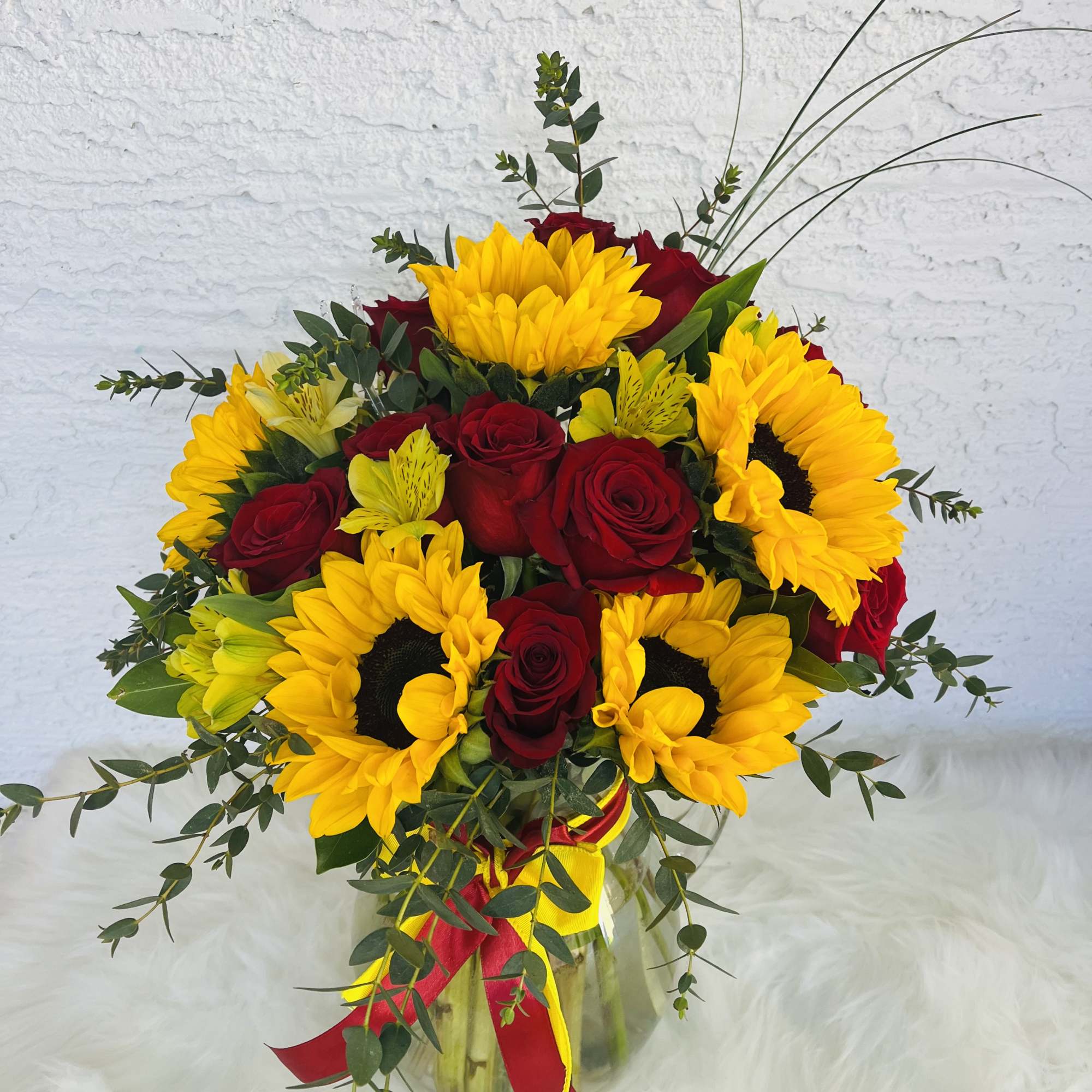 Bouquet of red roses and yellow sunflowers in a glass vase