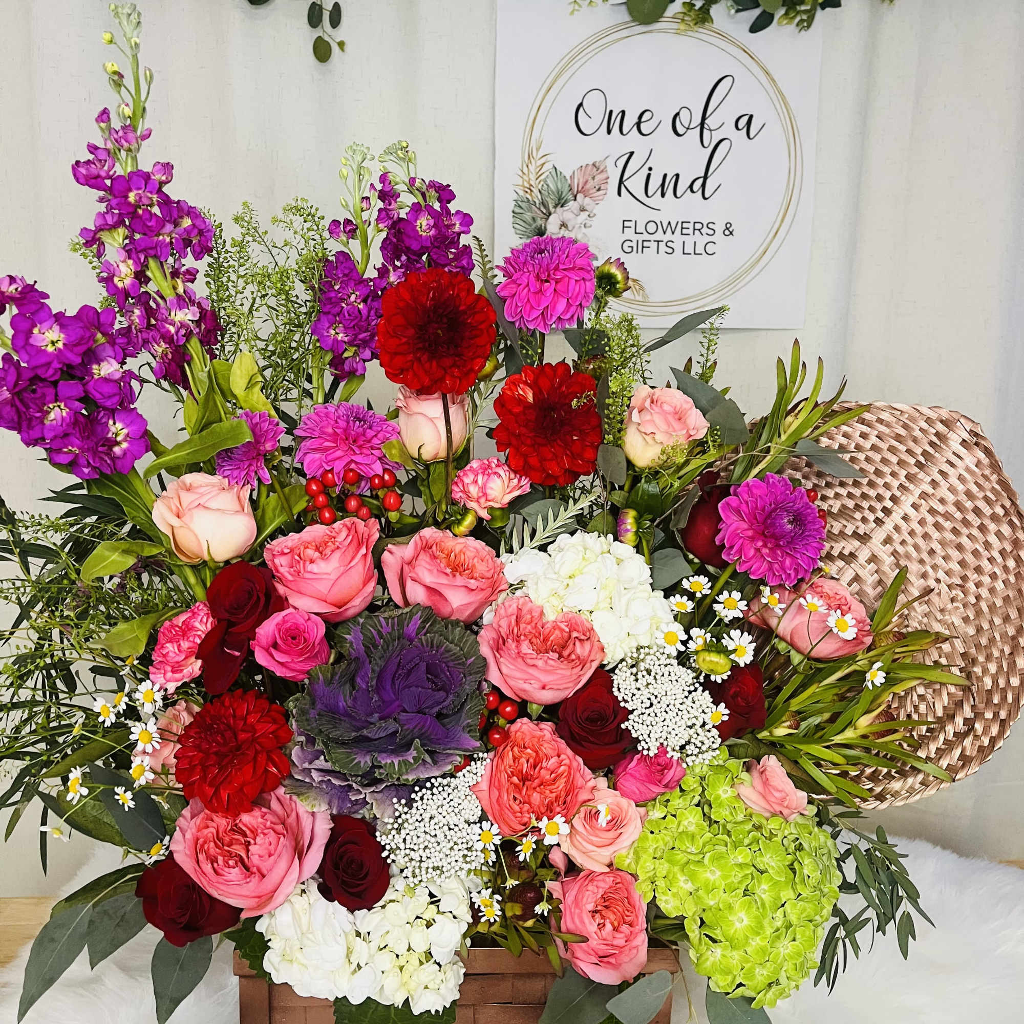 Mixed bouquet in a wooden basket with pink, red, purple, and white flowers