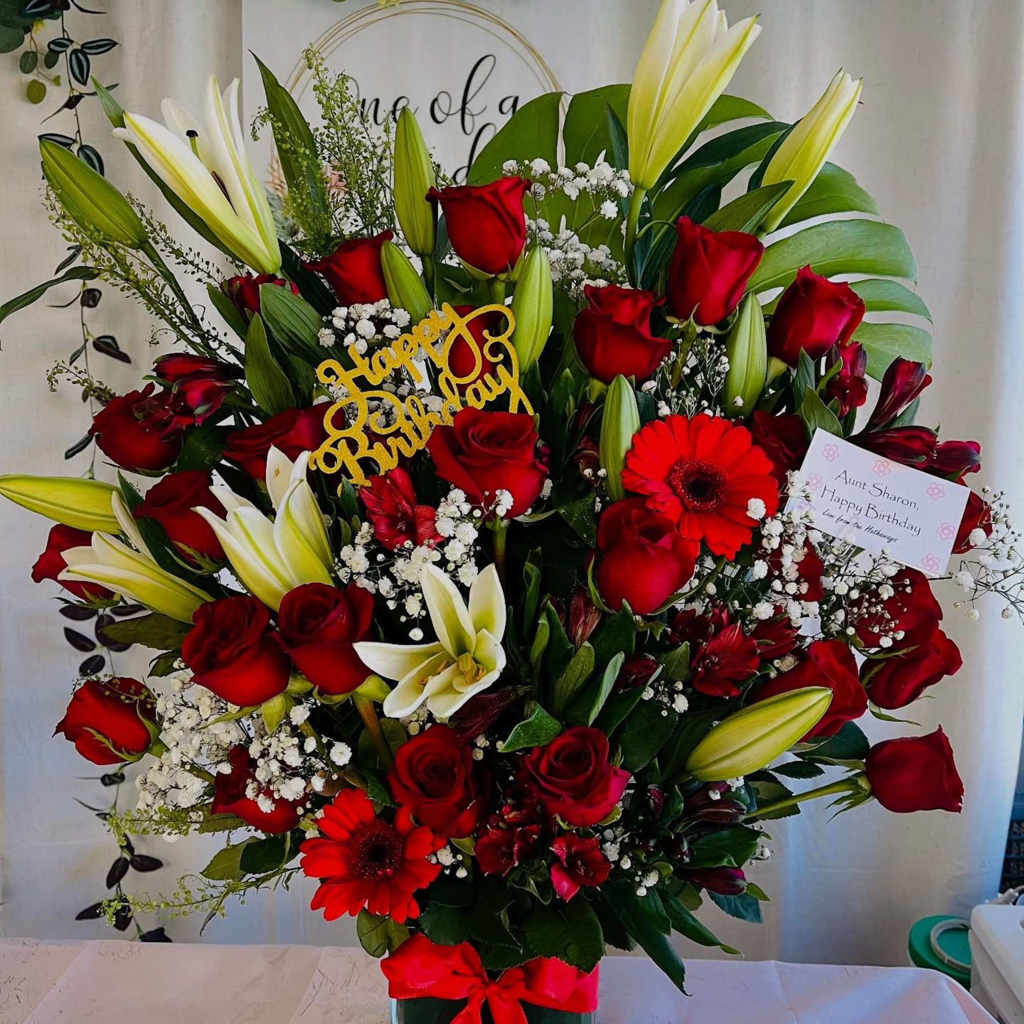 Red roses and white lilies in a glass vase with a birthday sign