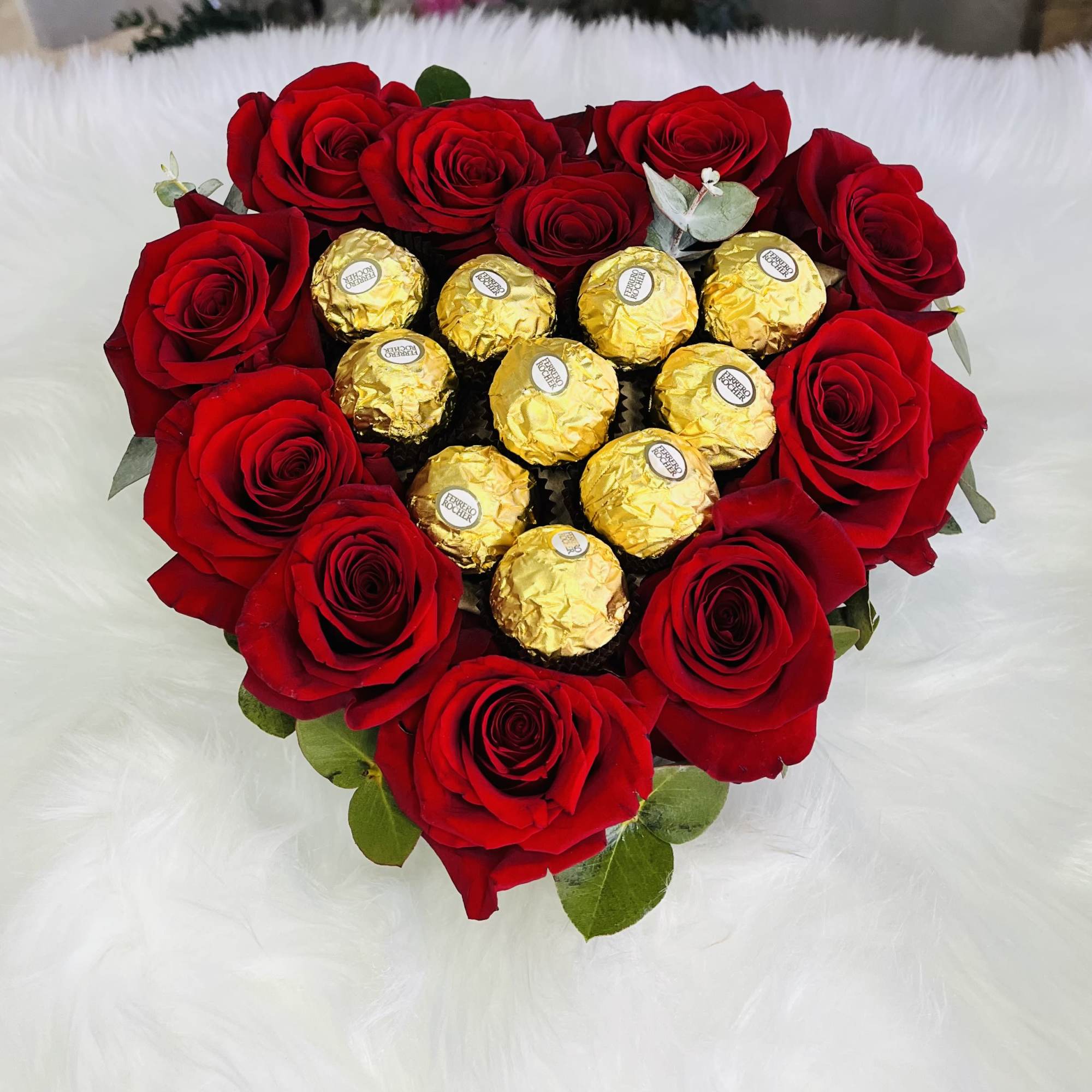 Heart-shaped bouquet of red roses with gold-wrapped chocolates