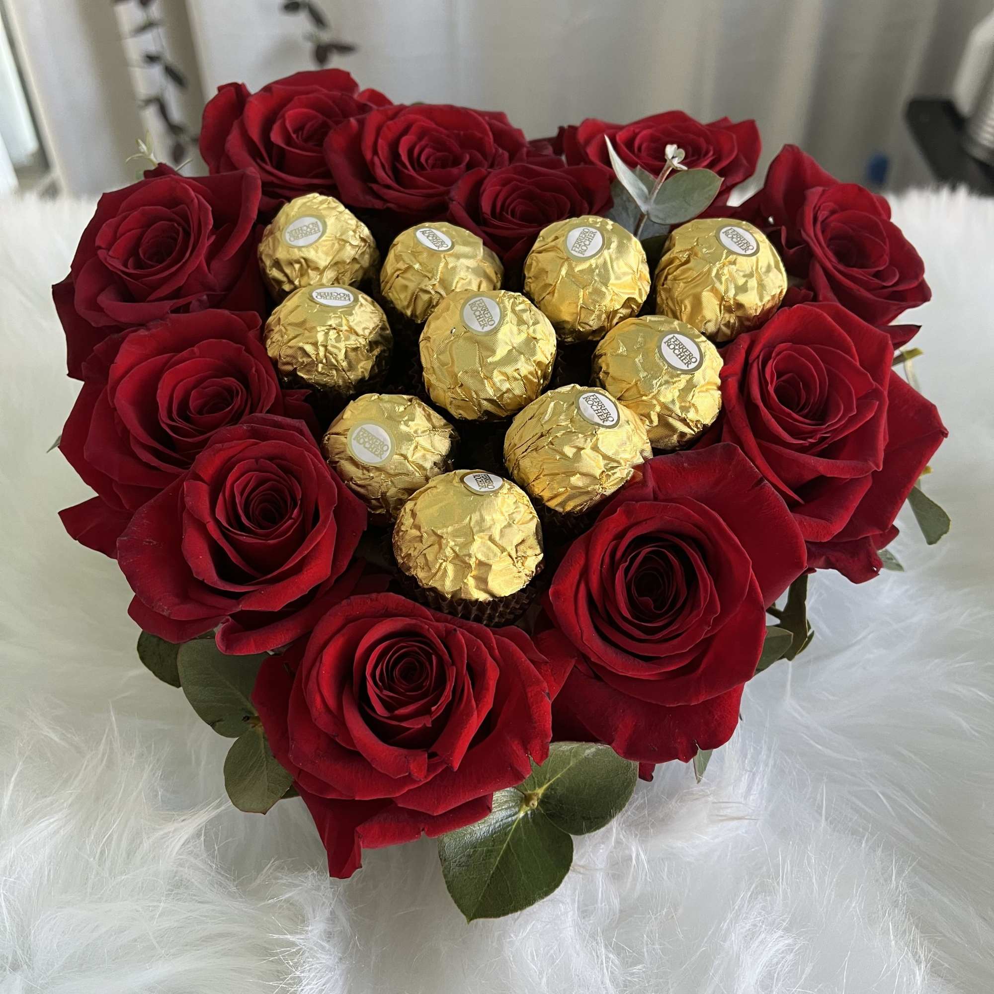 Heart-shaped bouquet of red roses with gold-wrapped chocolates in the center