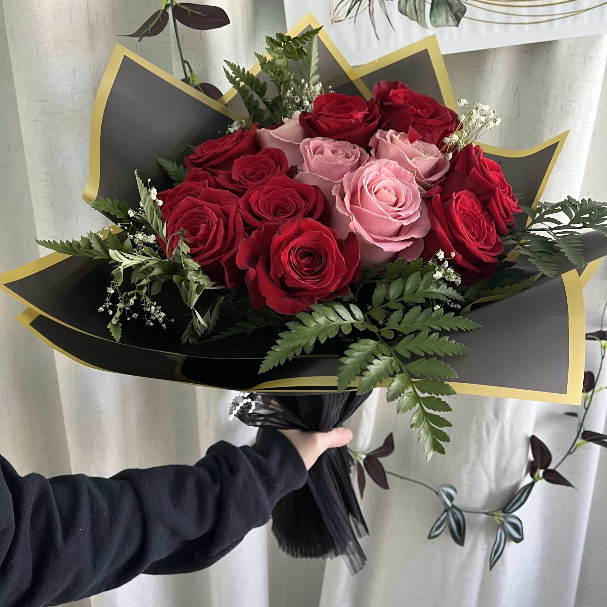 Bouquet of red and pink roses wrapped in black paper with gold trim