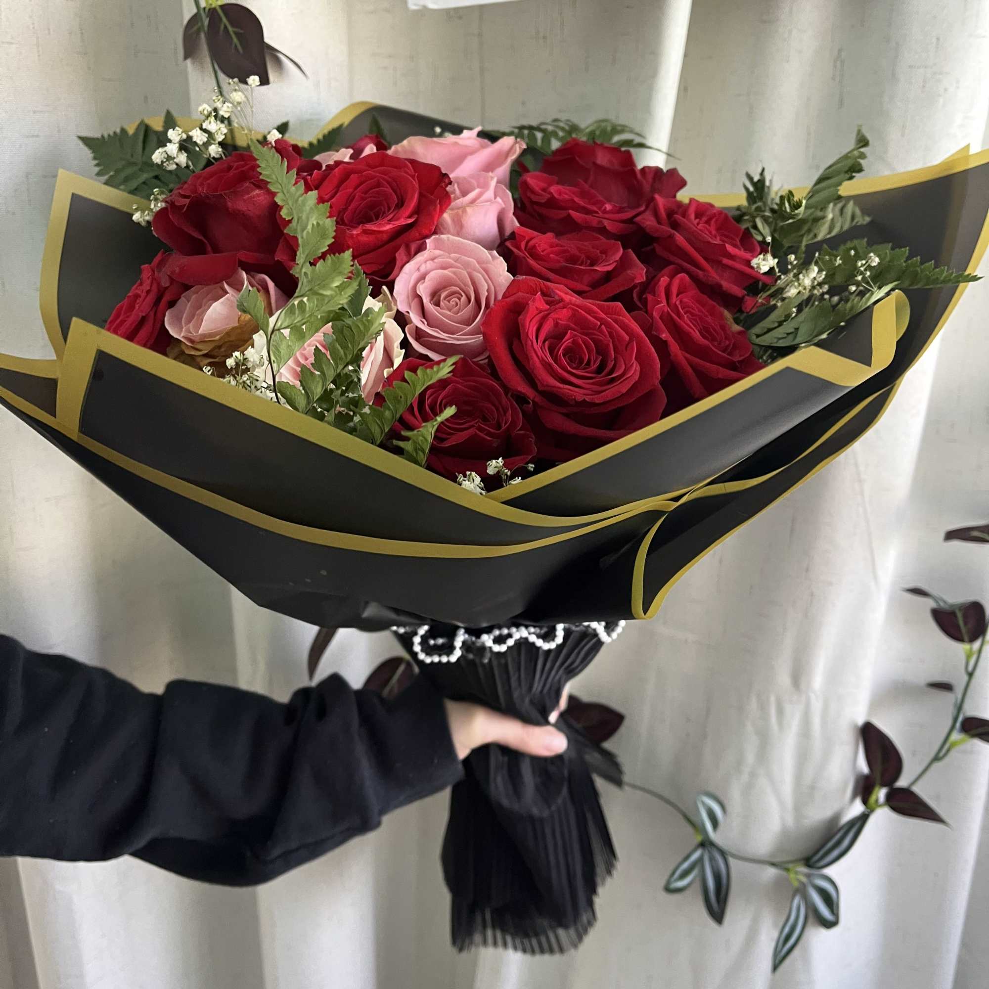 Bouquet of red and pink roses wrapped in black paper with gold trim, photo 2 of 3