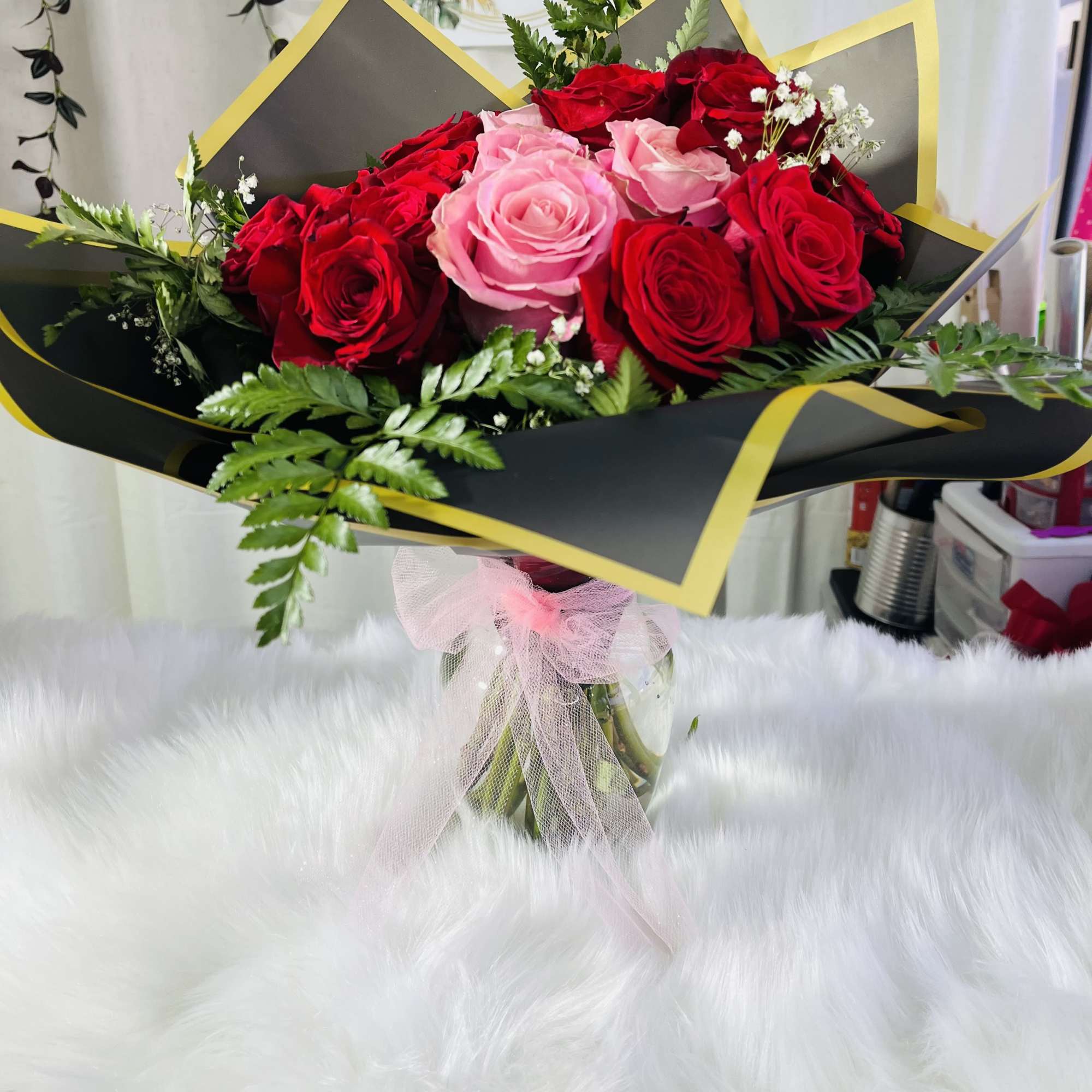 Bouquet of red and pink roses wrapped in black paper with yellow trim