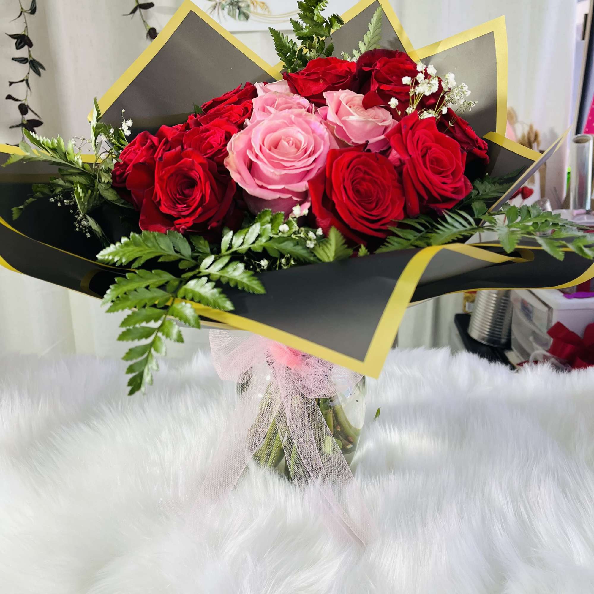 Bouquet of red and pink roses wrapped in black paper with gold trim