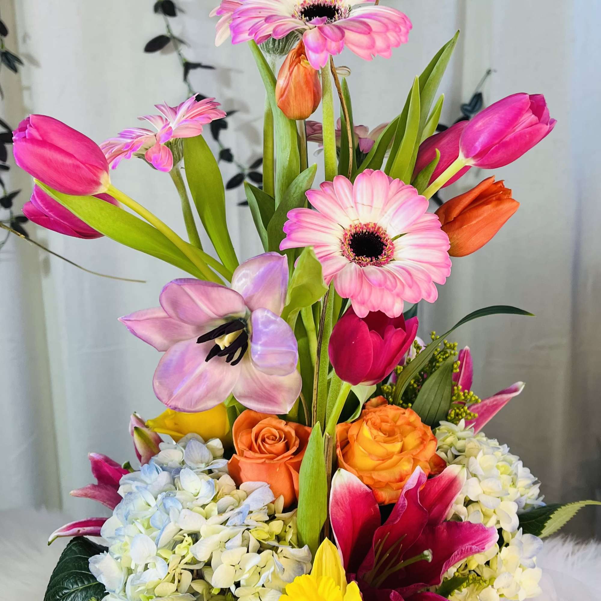 Bright mixed bouquet in a pink wrapped container with tulips and gerbera daisies