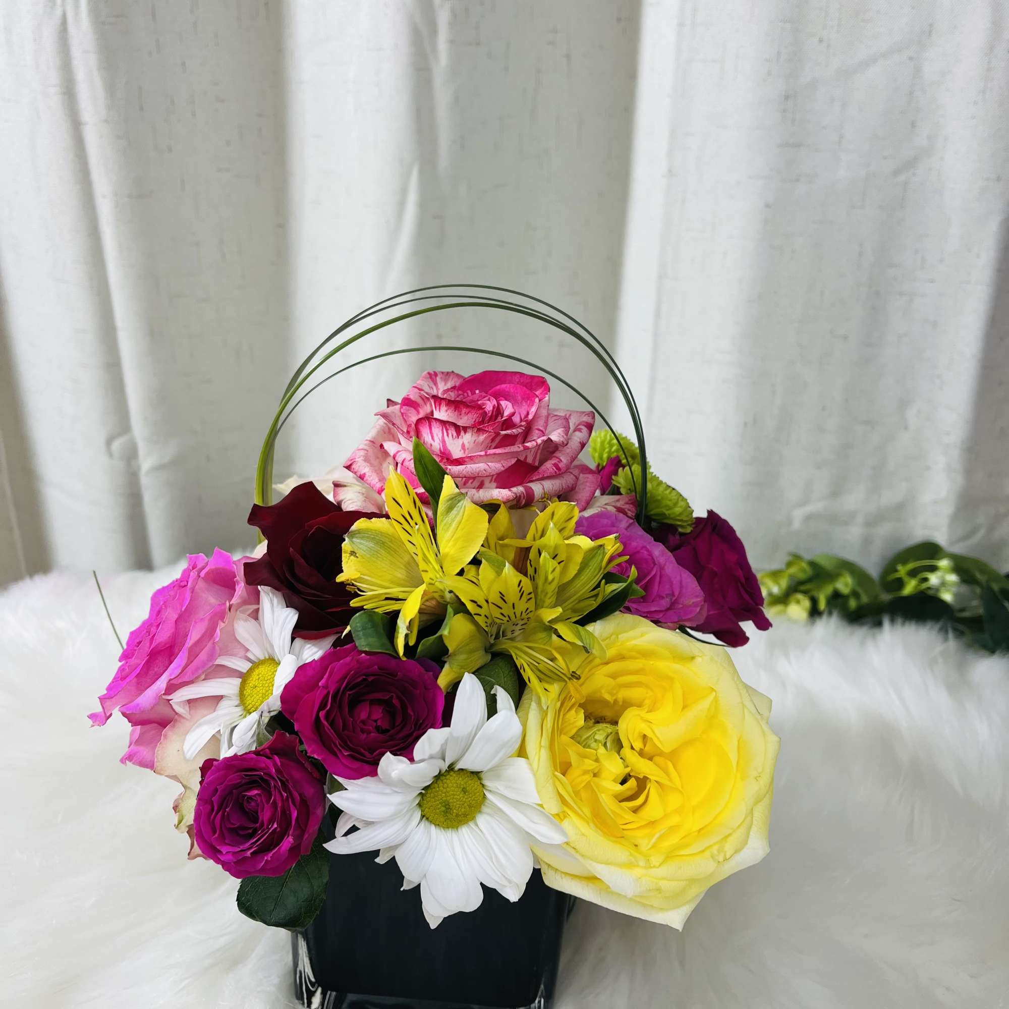 Colorful mixed flower basket with roses and daisies in a black container
