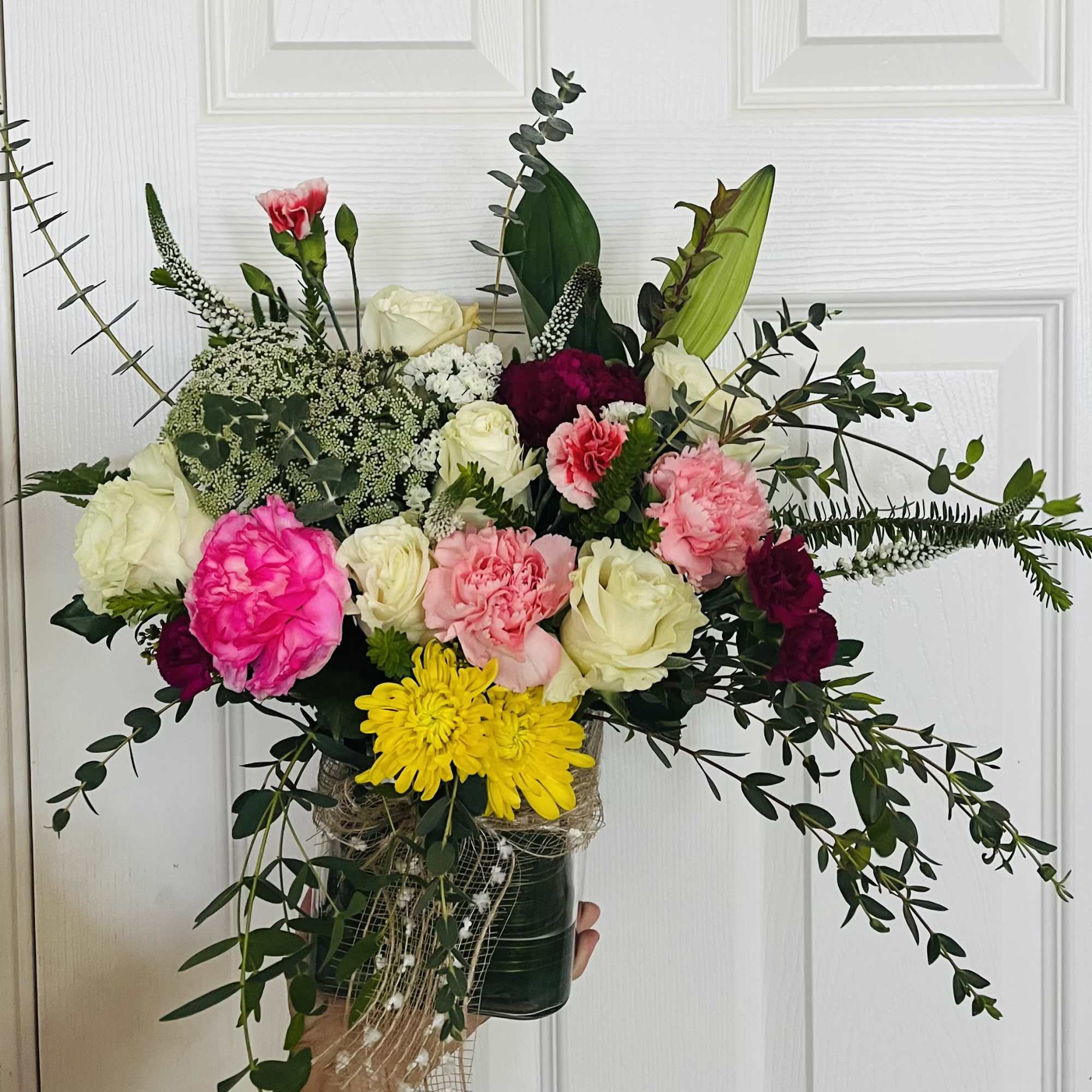 Mixed bouquet of roses, carnations, and chrysanthemums in a dark vase