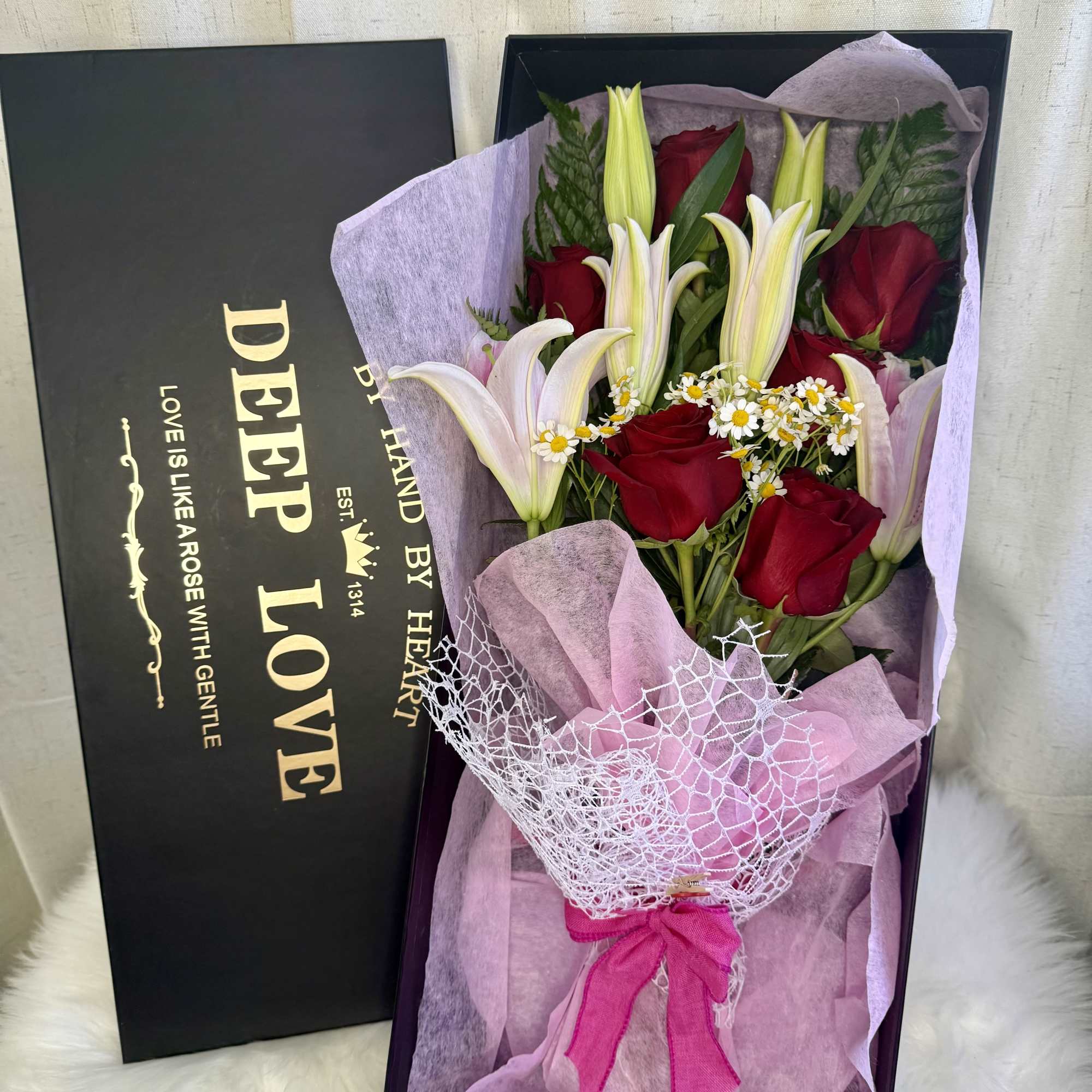 Red roses and white lilies in a gift box with pink wrapping