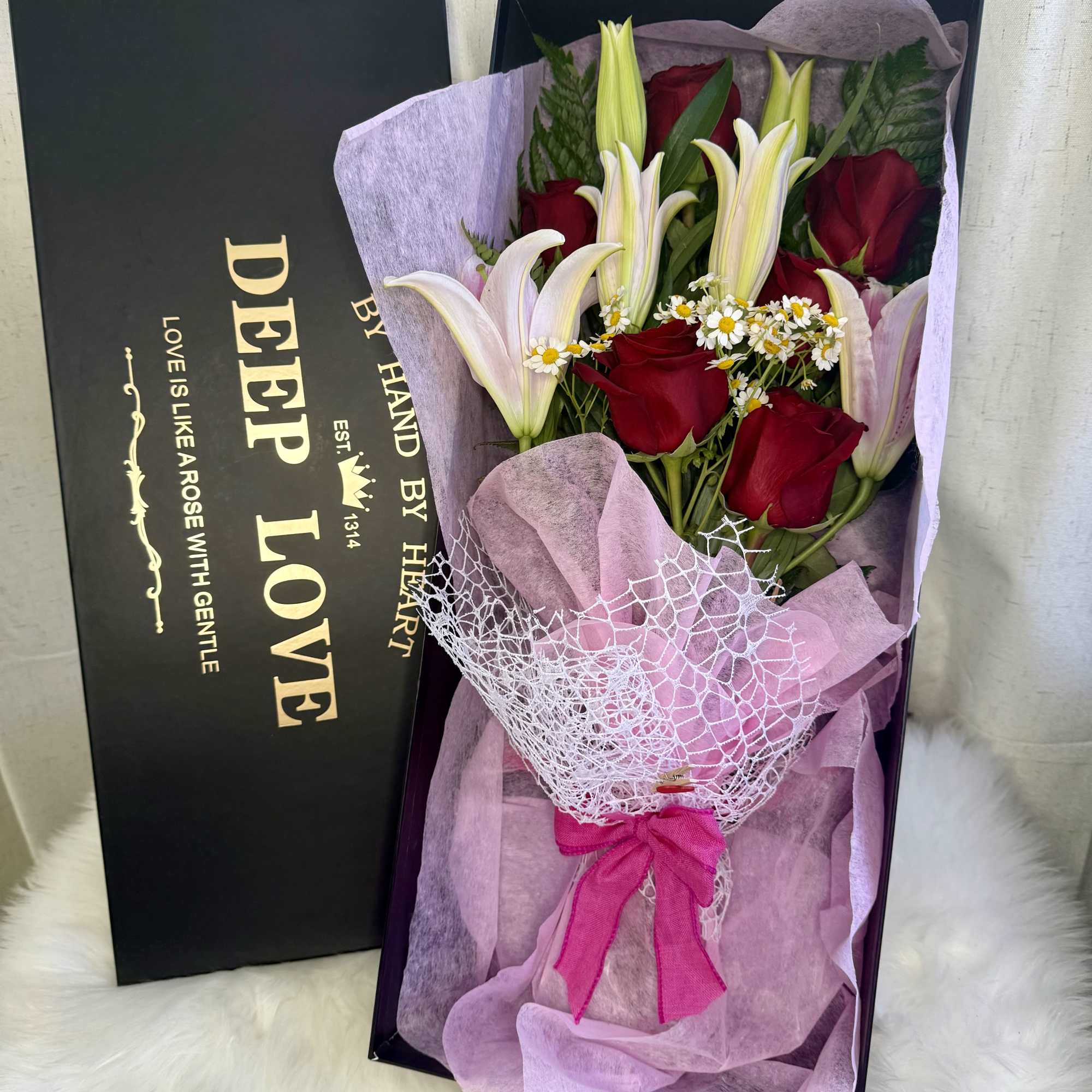 Boxed bouquet of red roses and white lilies with a pink ribbon