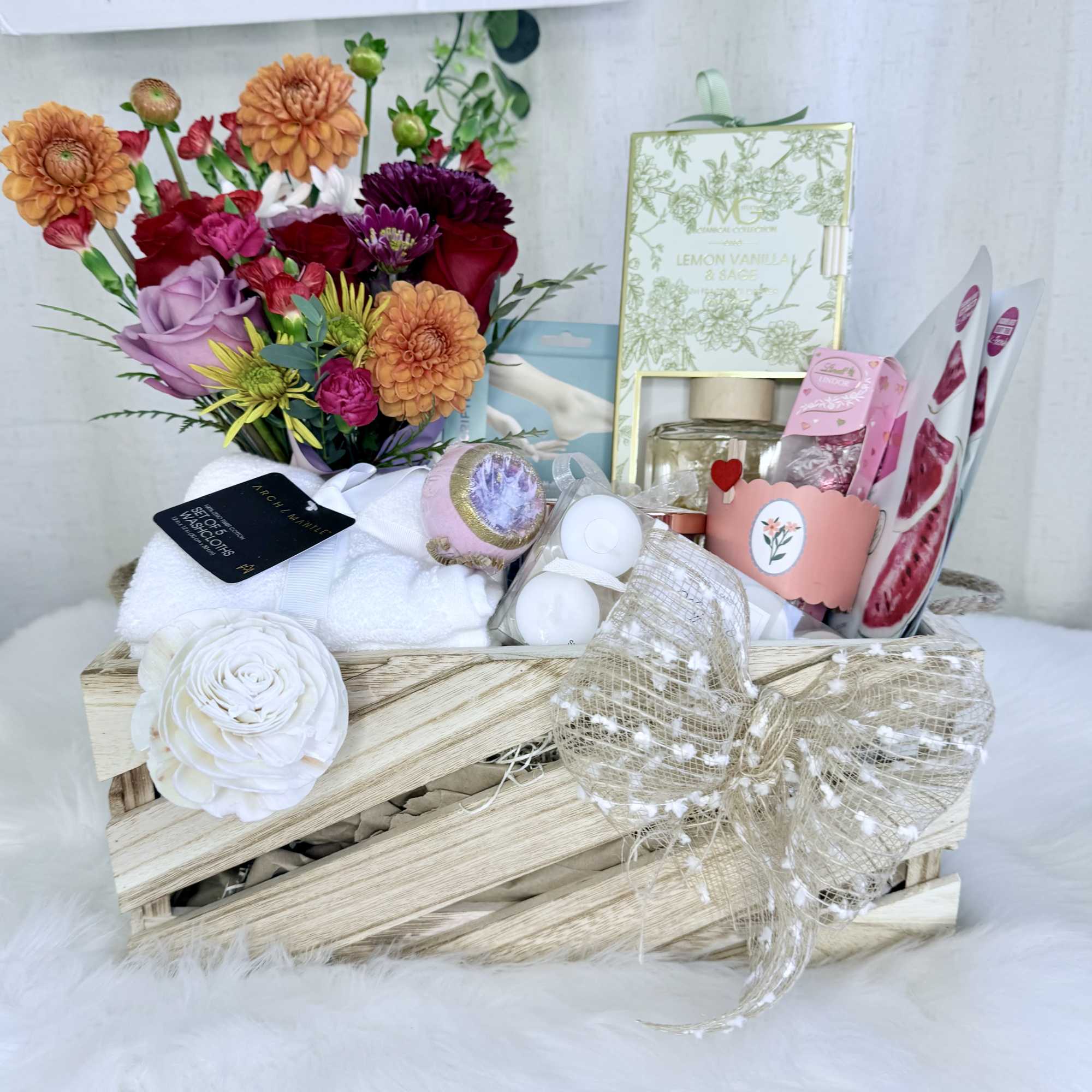 Gift basket with flowers, towels, candles, and bath items in a wooden crate