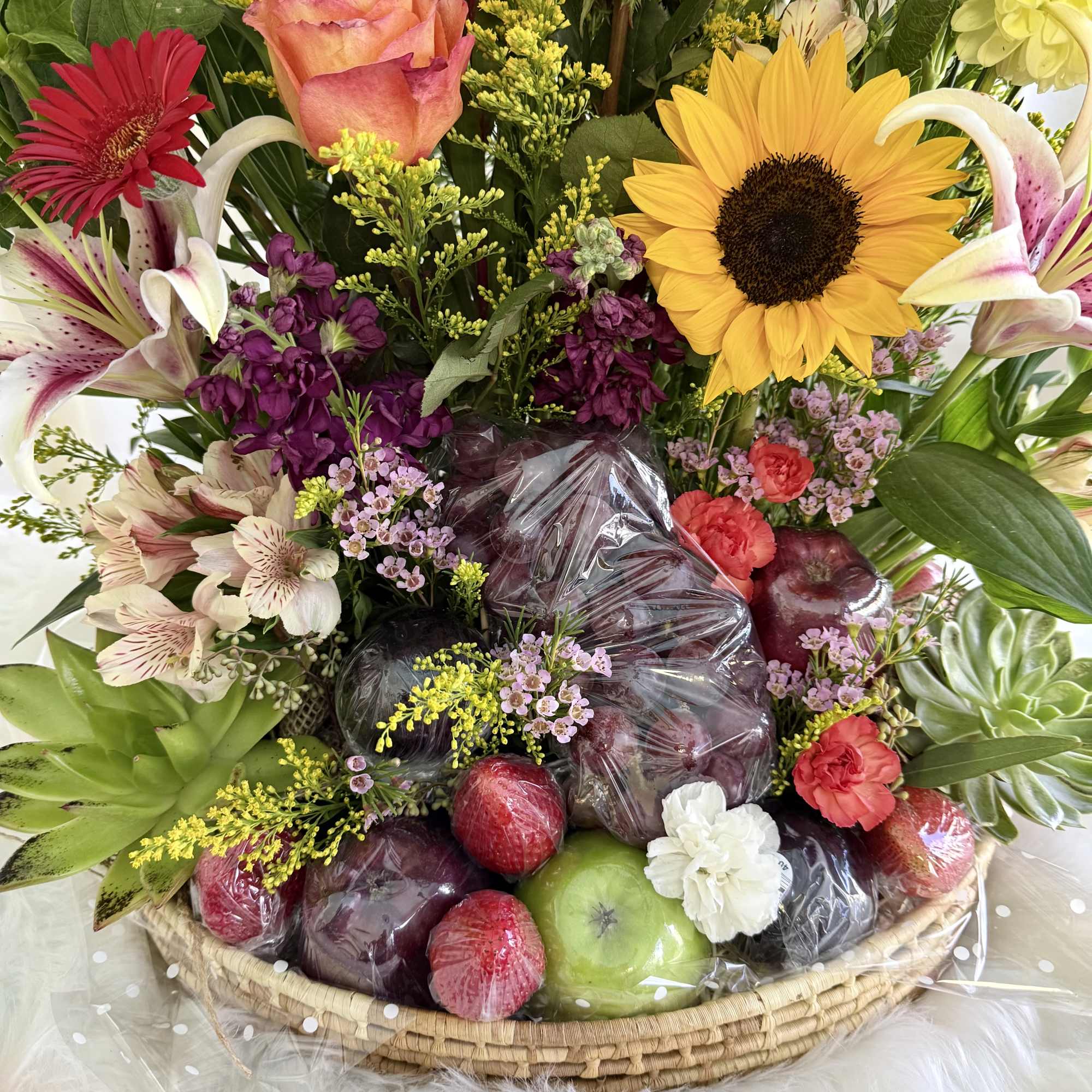 Mixed flower basket with fruit arranged at the base