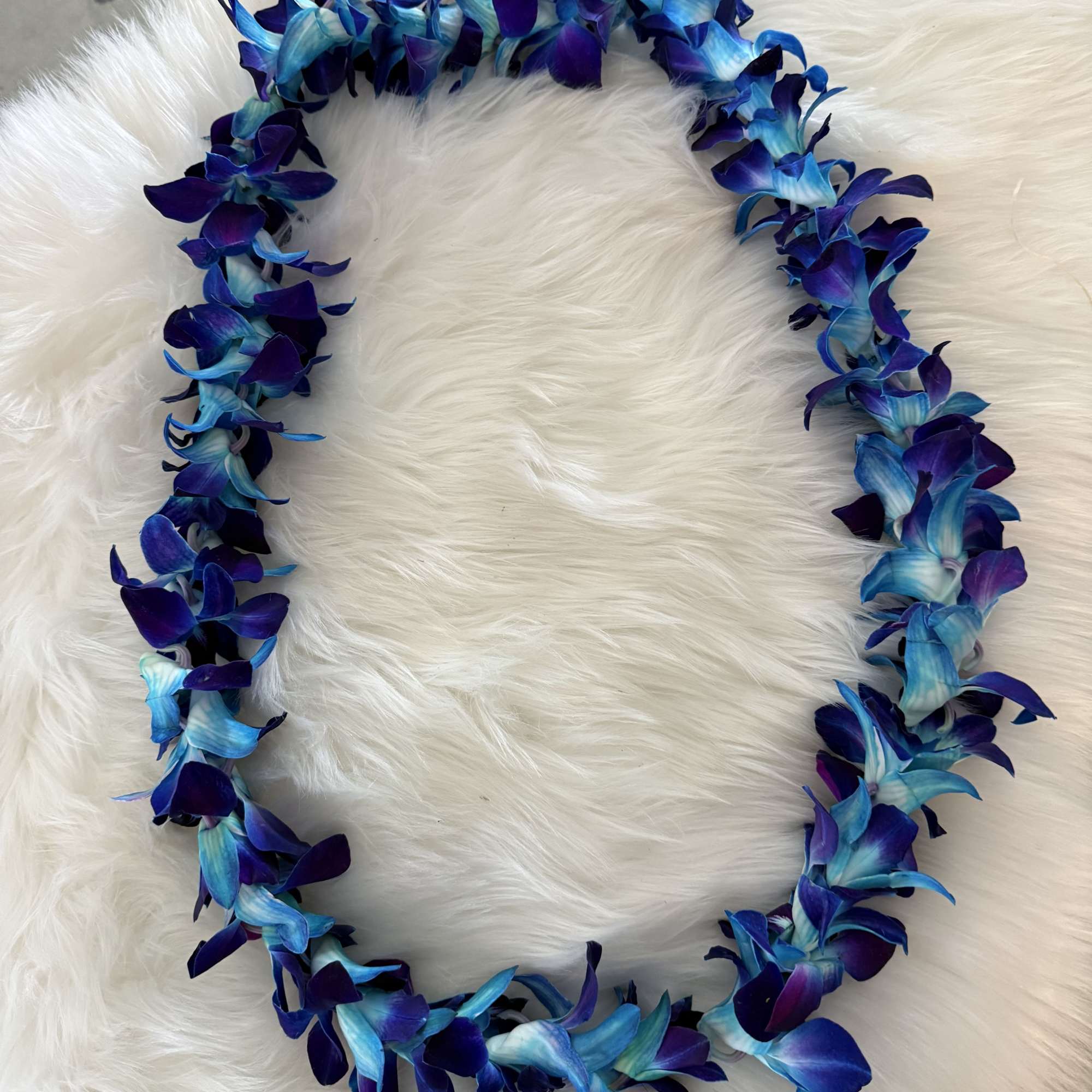 Blue and purple flower lei on a white fur background