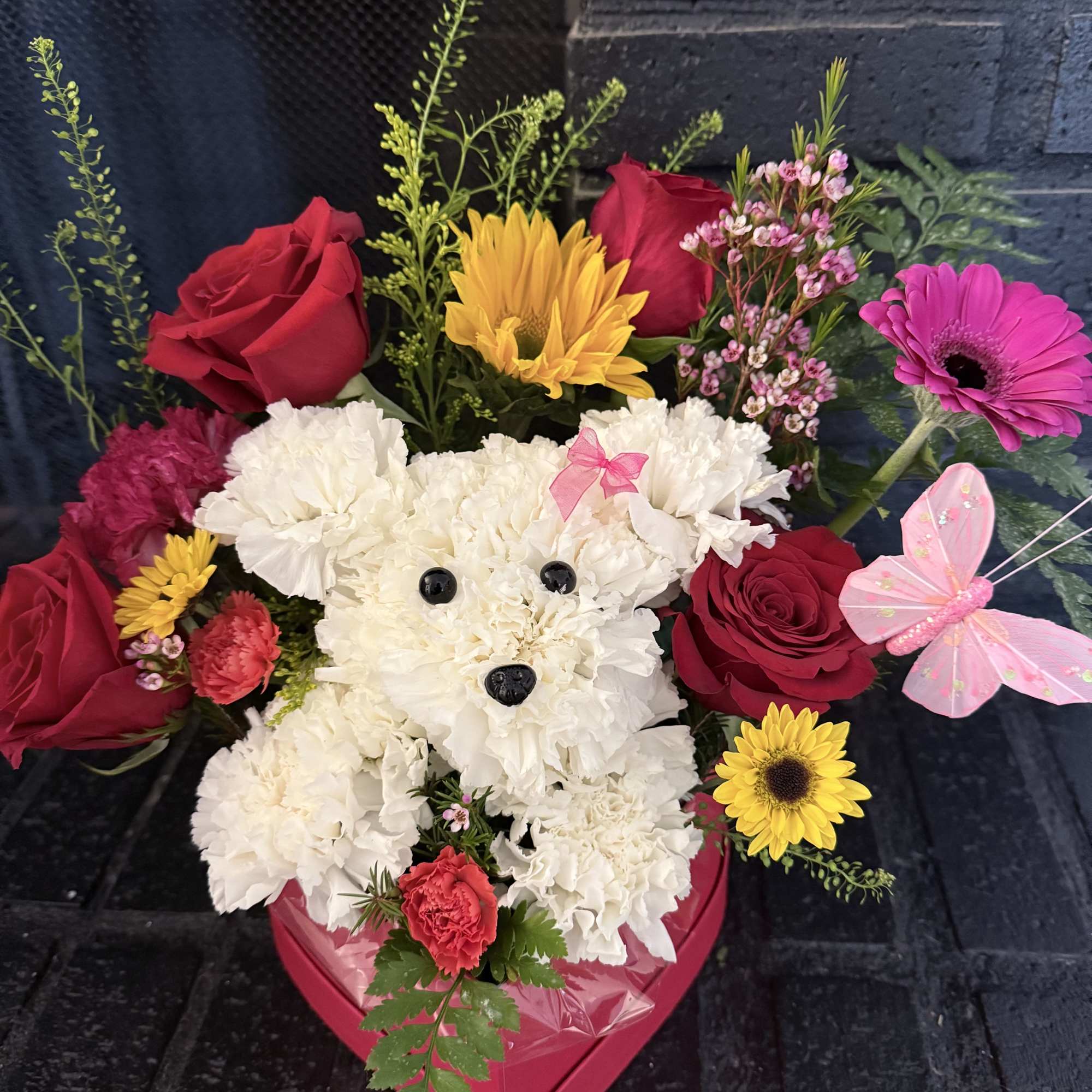 Teddy bear made of white carnations with roses and daisies in a pink heart box