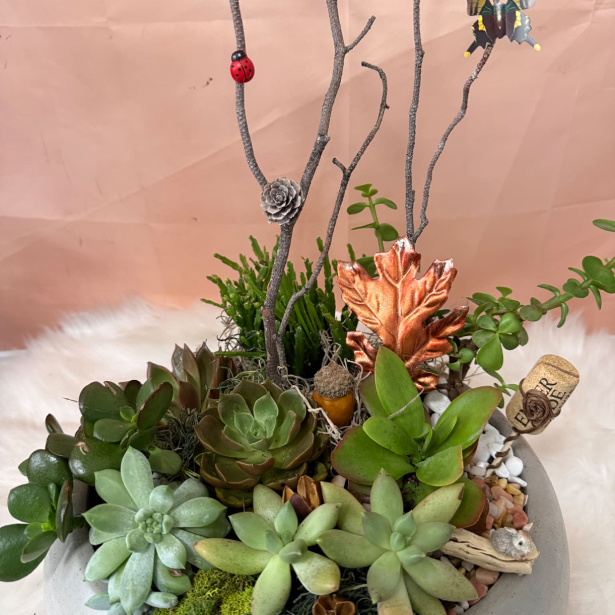 Succulent arrangement in a shallow bowl with decorative branches and ornaments