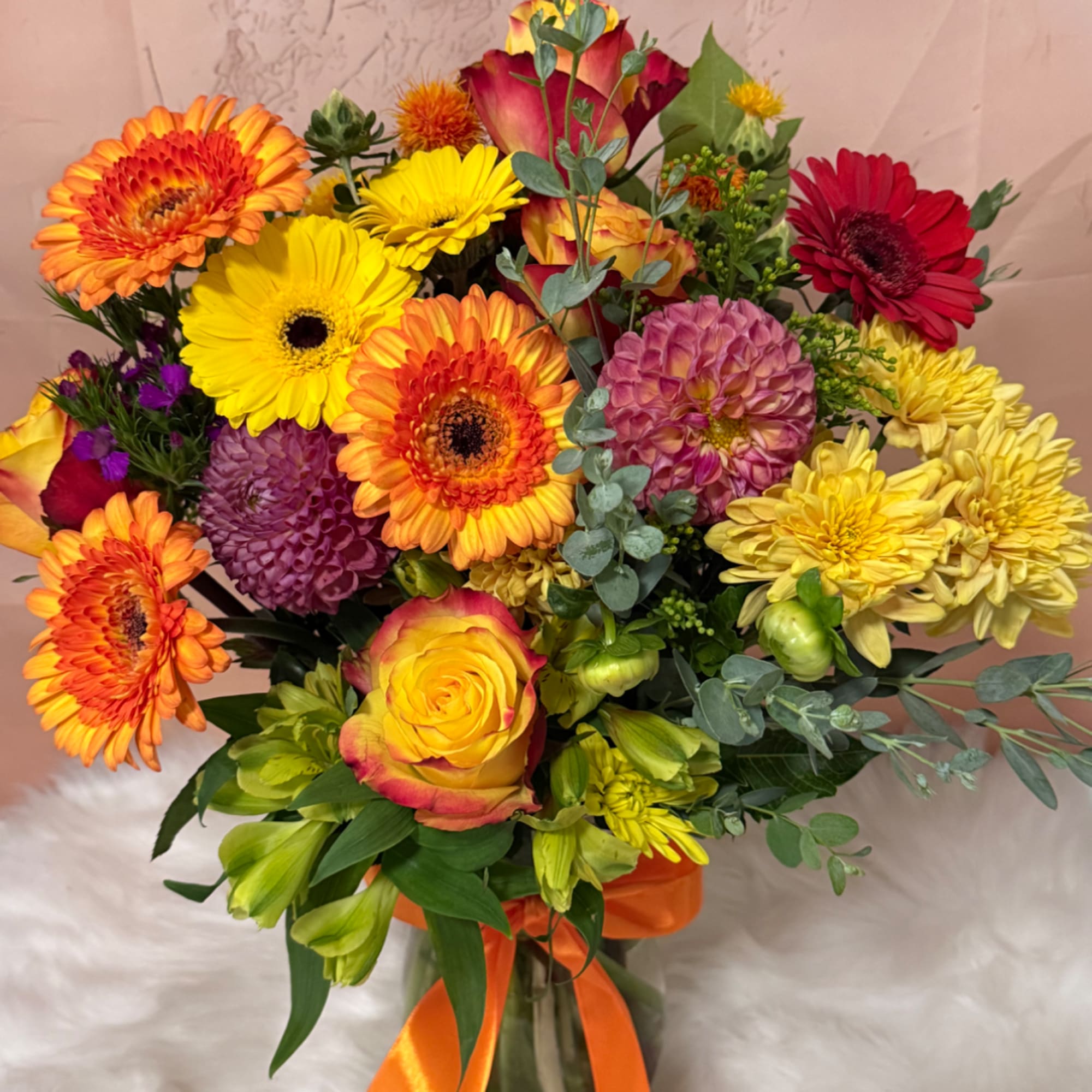 Bright mixed bouquet with gerbera daisies, roses, and a glass vase