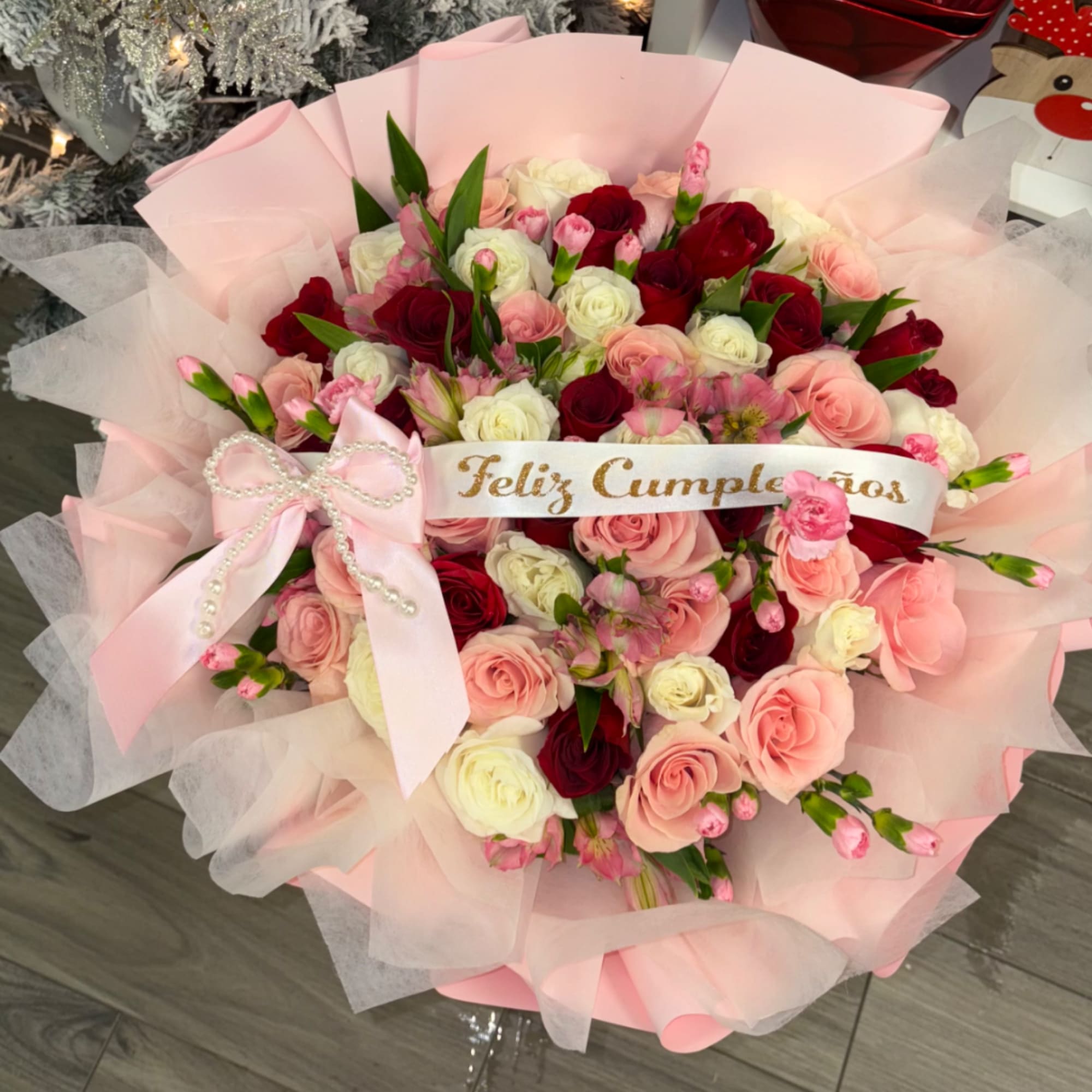 Bouquet of pink, red, and white roses with a pink ribbon