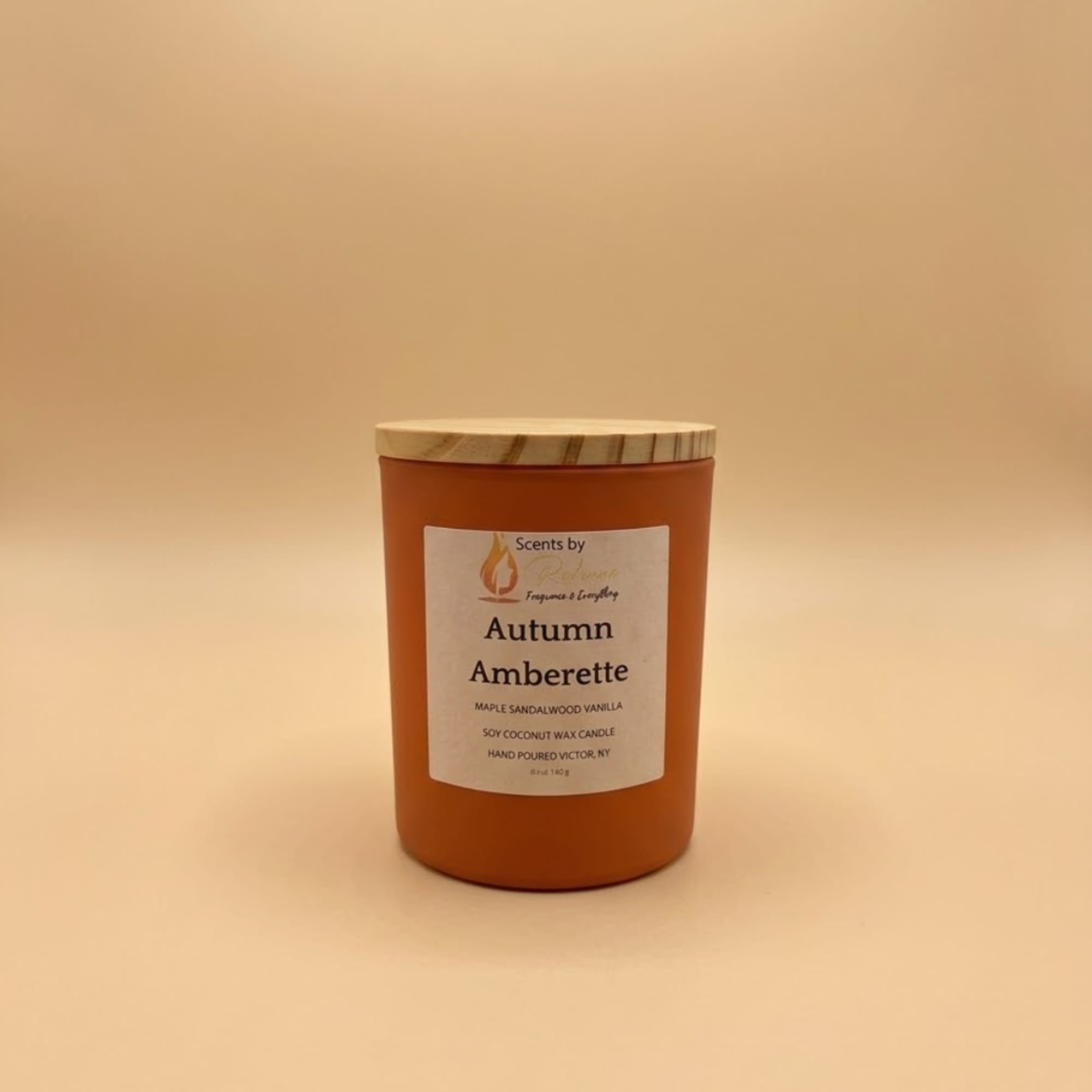Orange candle jar with a wooden lid on a beige background
