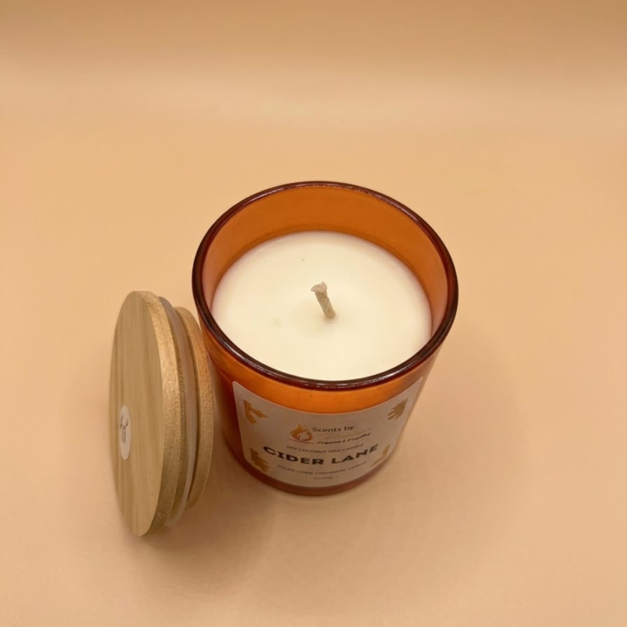Amber glass candle with a wooden lid on a beige background