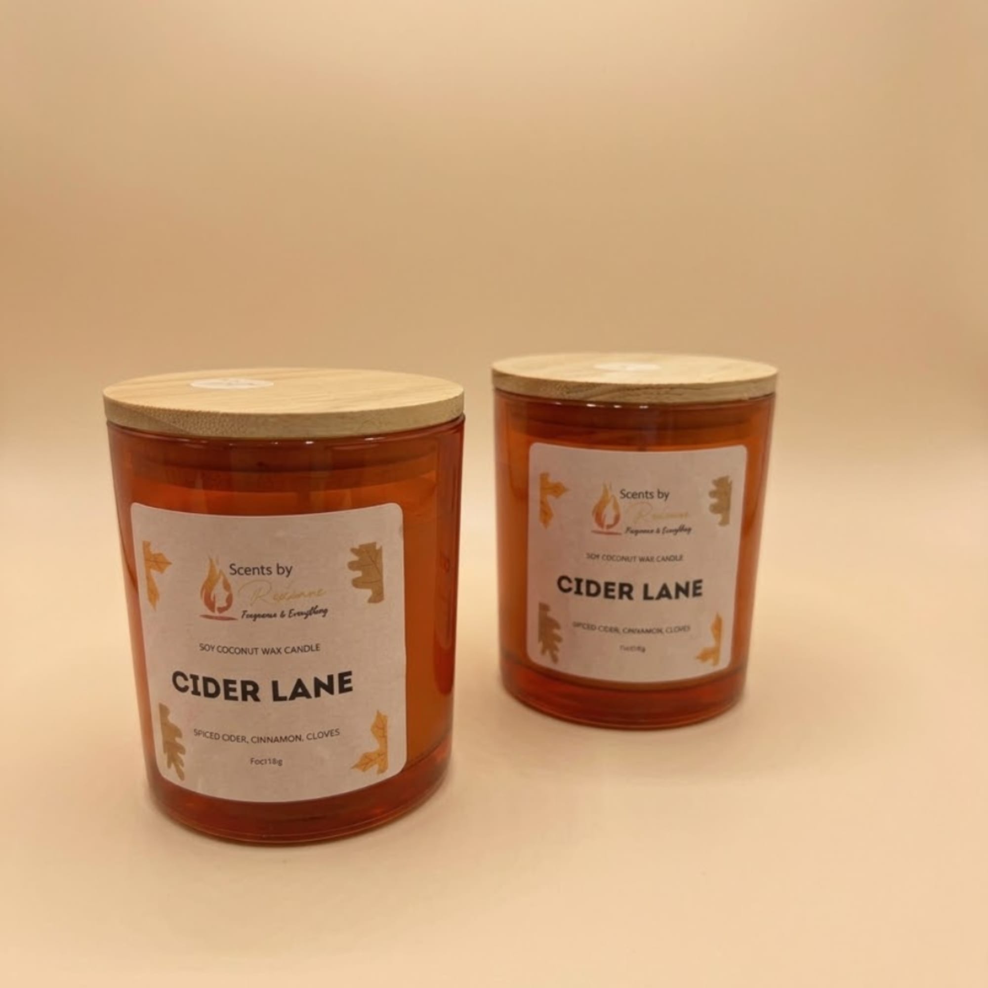 Two amber candles with wooden lids on a plain background