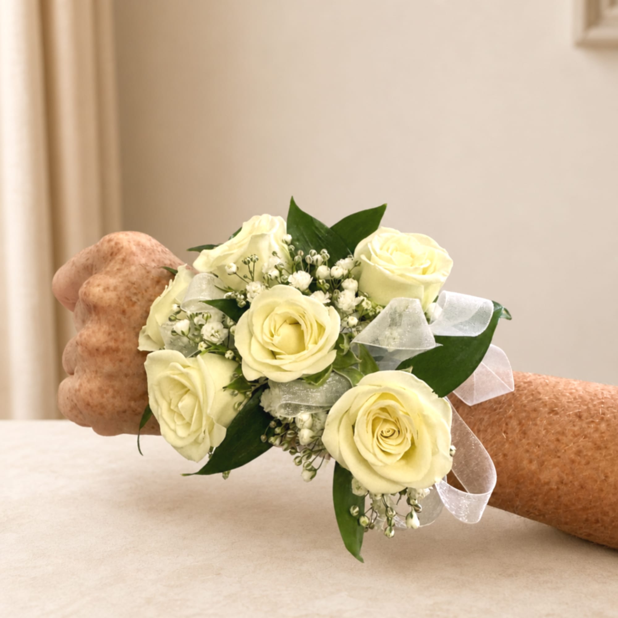 Cream rose wrist corsage with white ribbon on a person's wrist