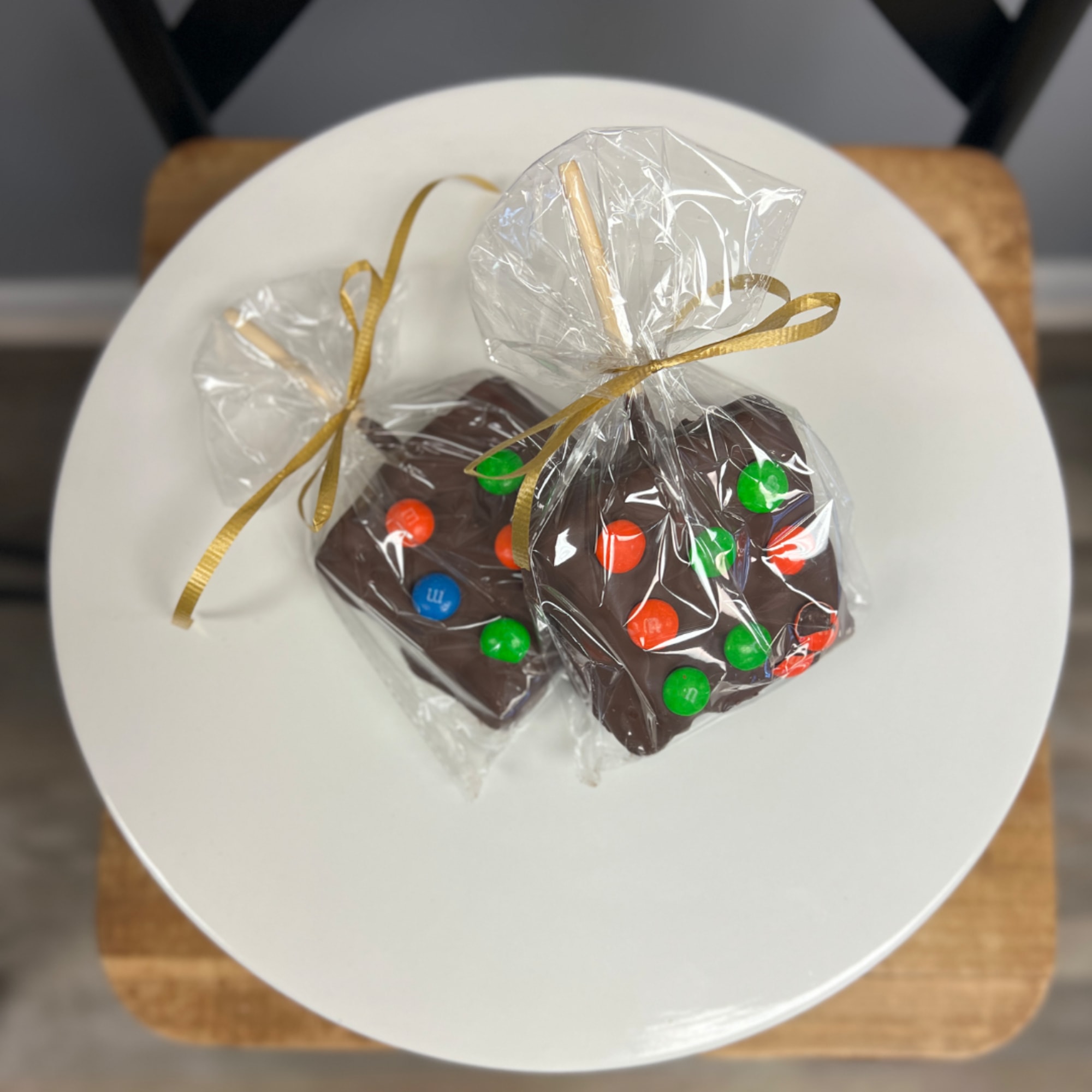 Two wrapped chocolate treats with colorful candy pieces on a white plate