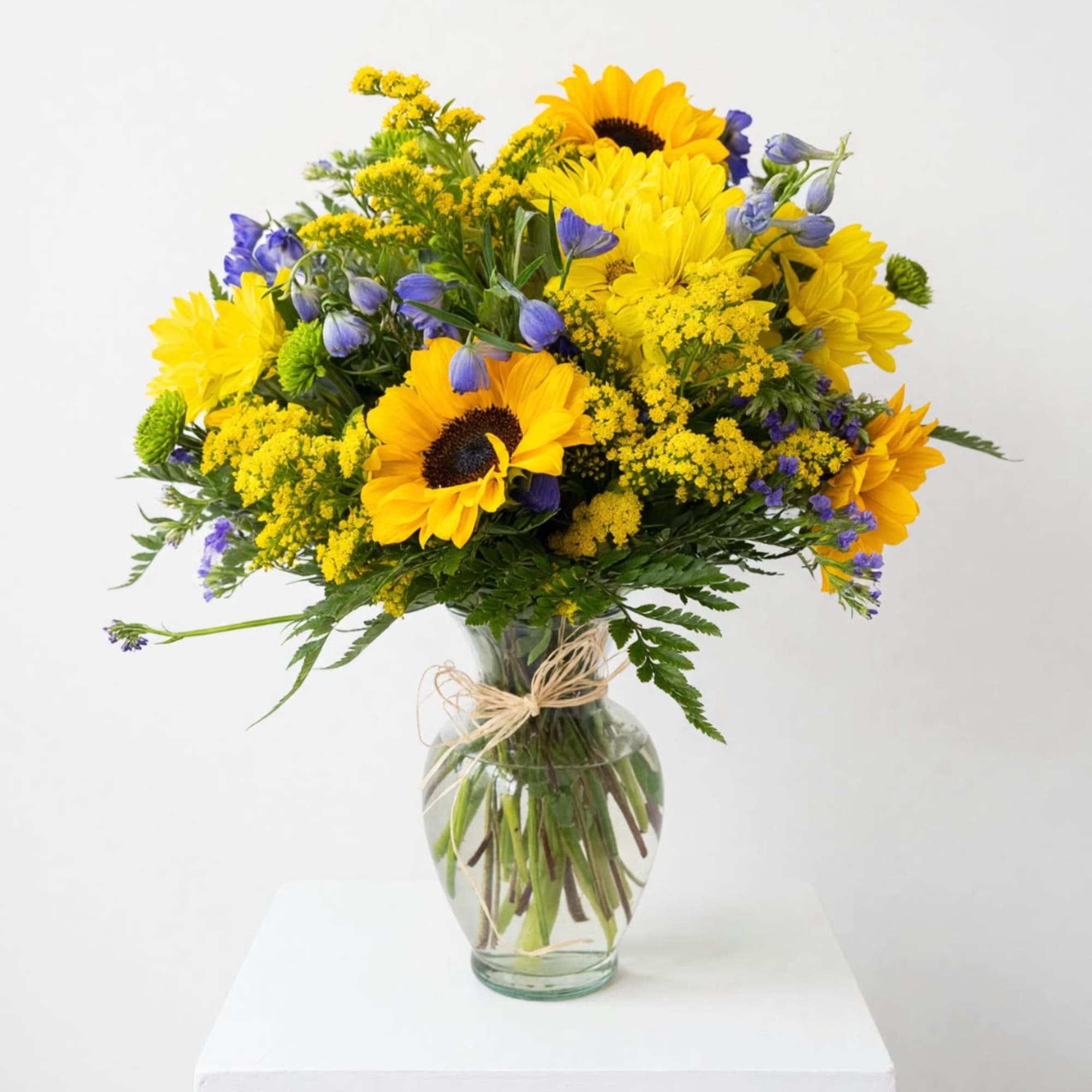 Yellow sunflowers and purple flowers in a glass vase