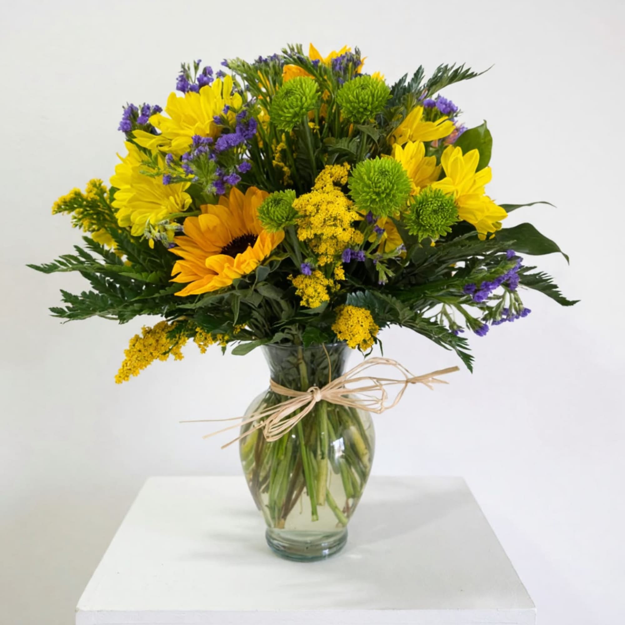 Yellow and purple mixed bouquet in a clear glass vase