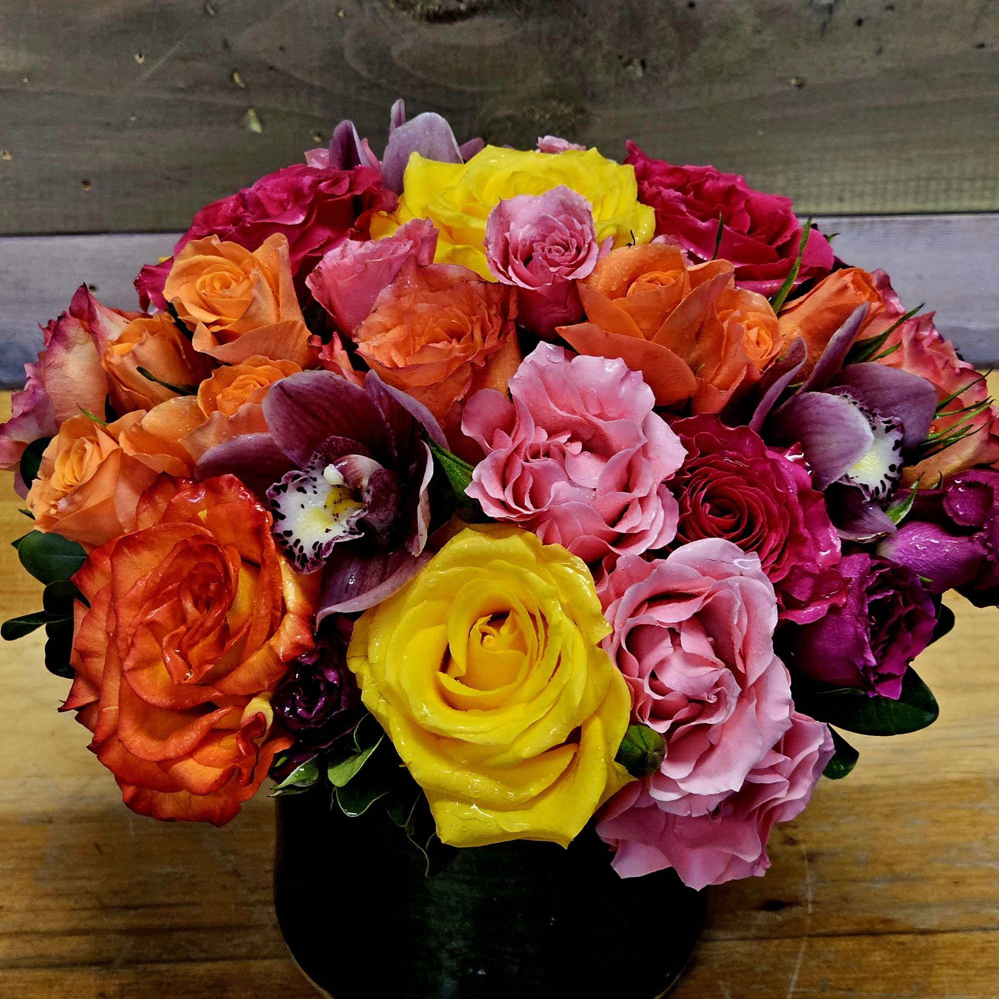 Colorful bouquet of roses and orchids in a black vase