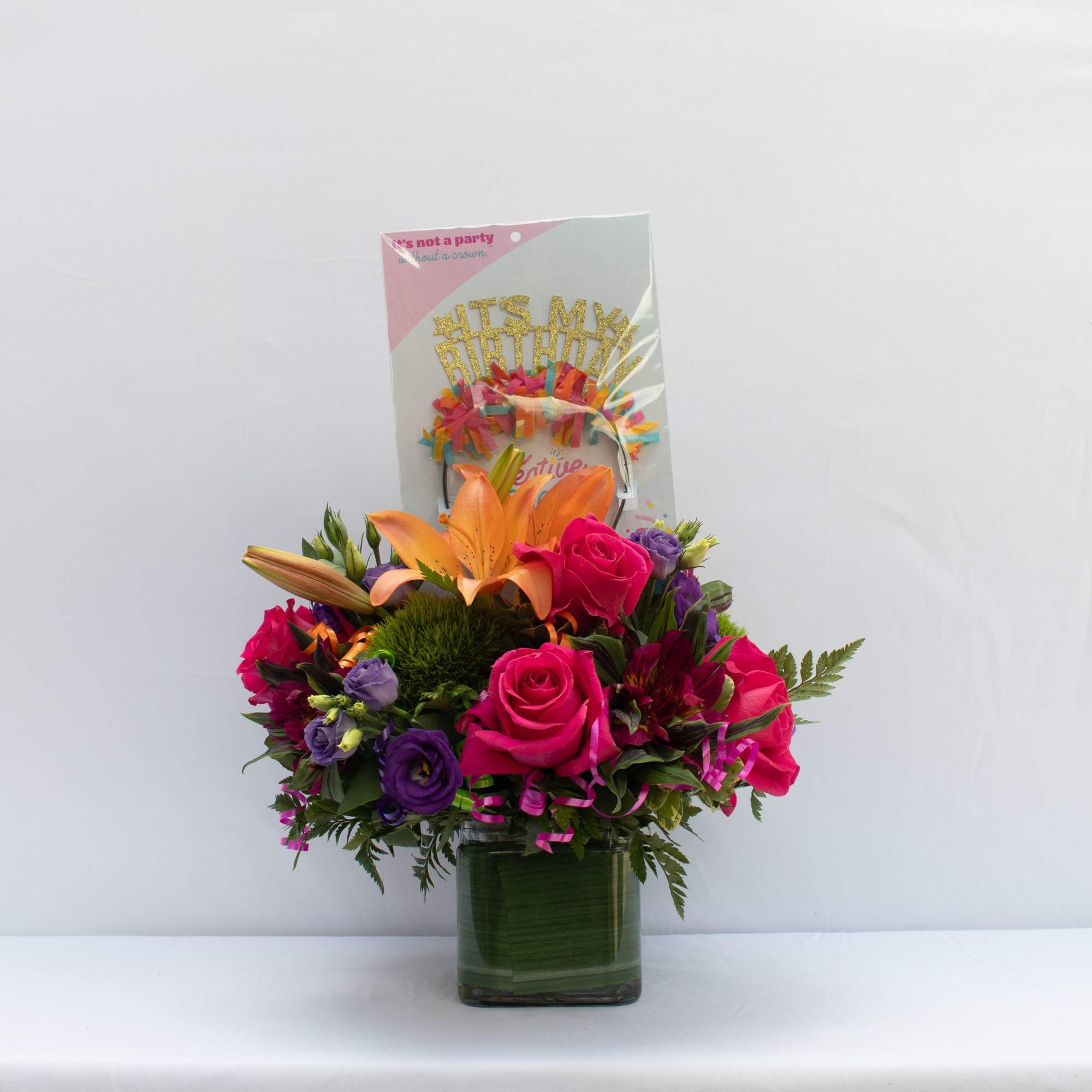 Bright mixed bouquet in a glass vase with a birthday card topper