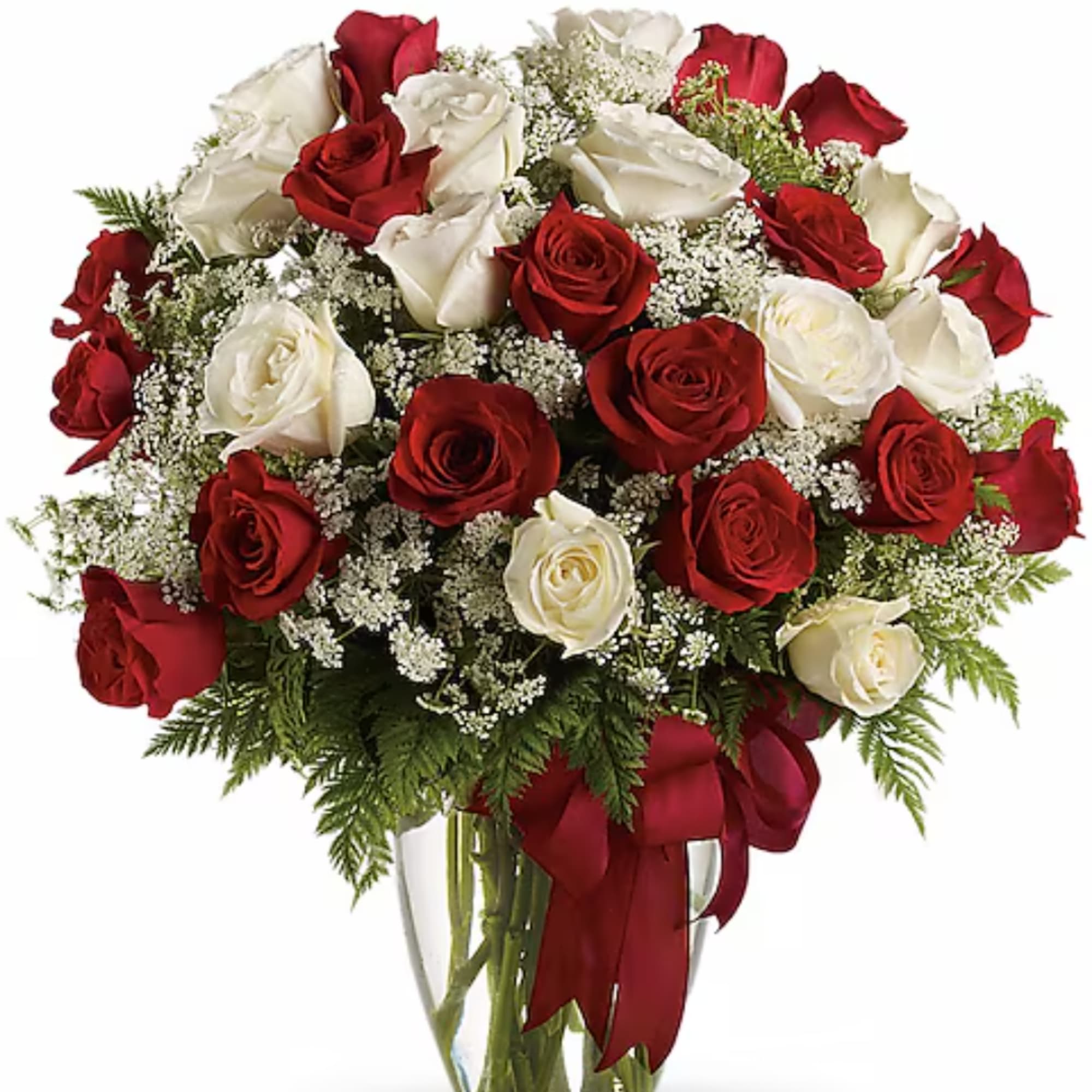 Red and white roses arranged in a clear glass vase with a red ribbon