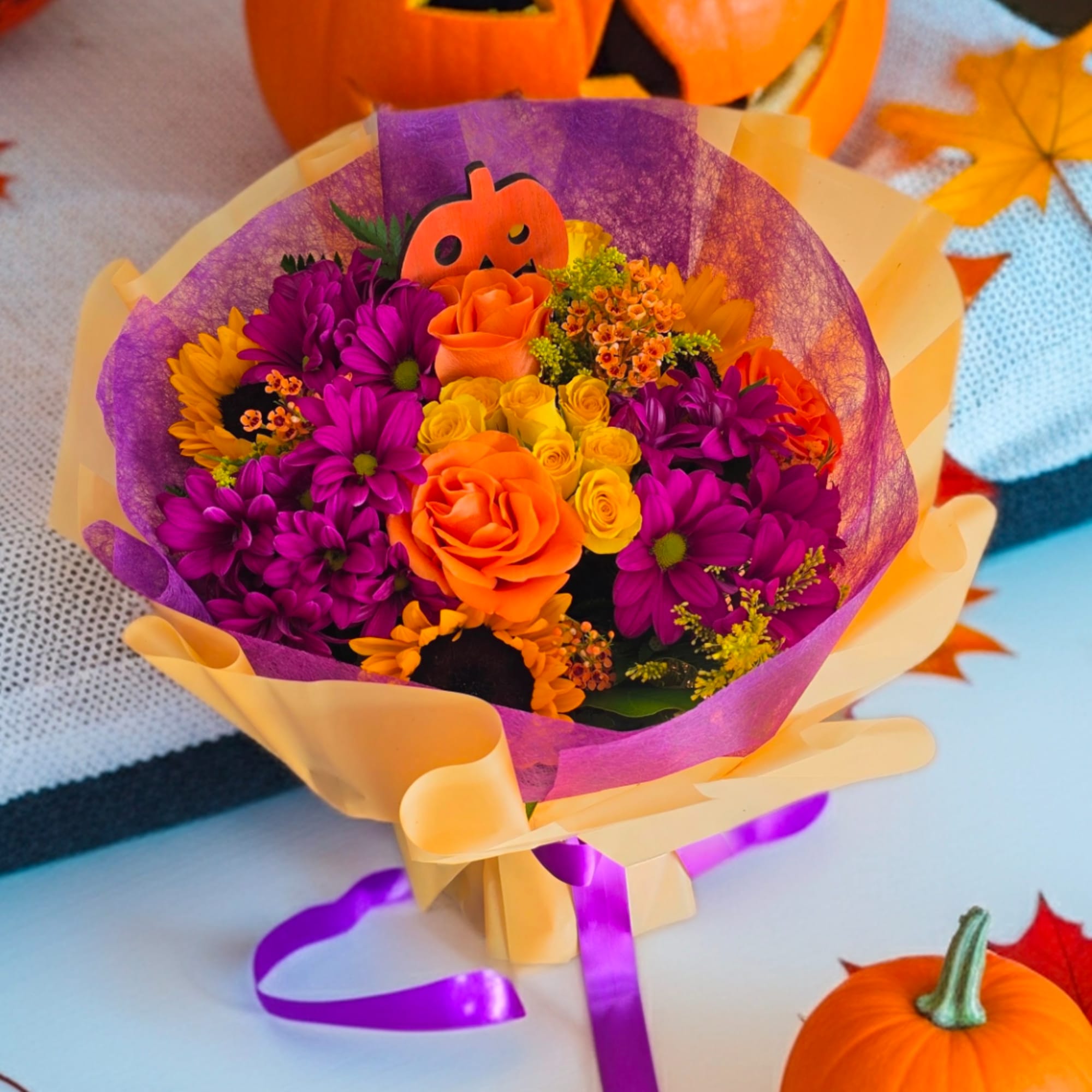 Bouquet of orange and purple flowers wrapped in yellow and purple paper