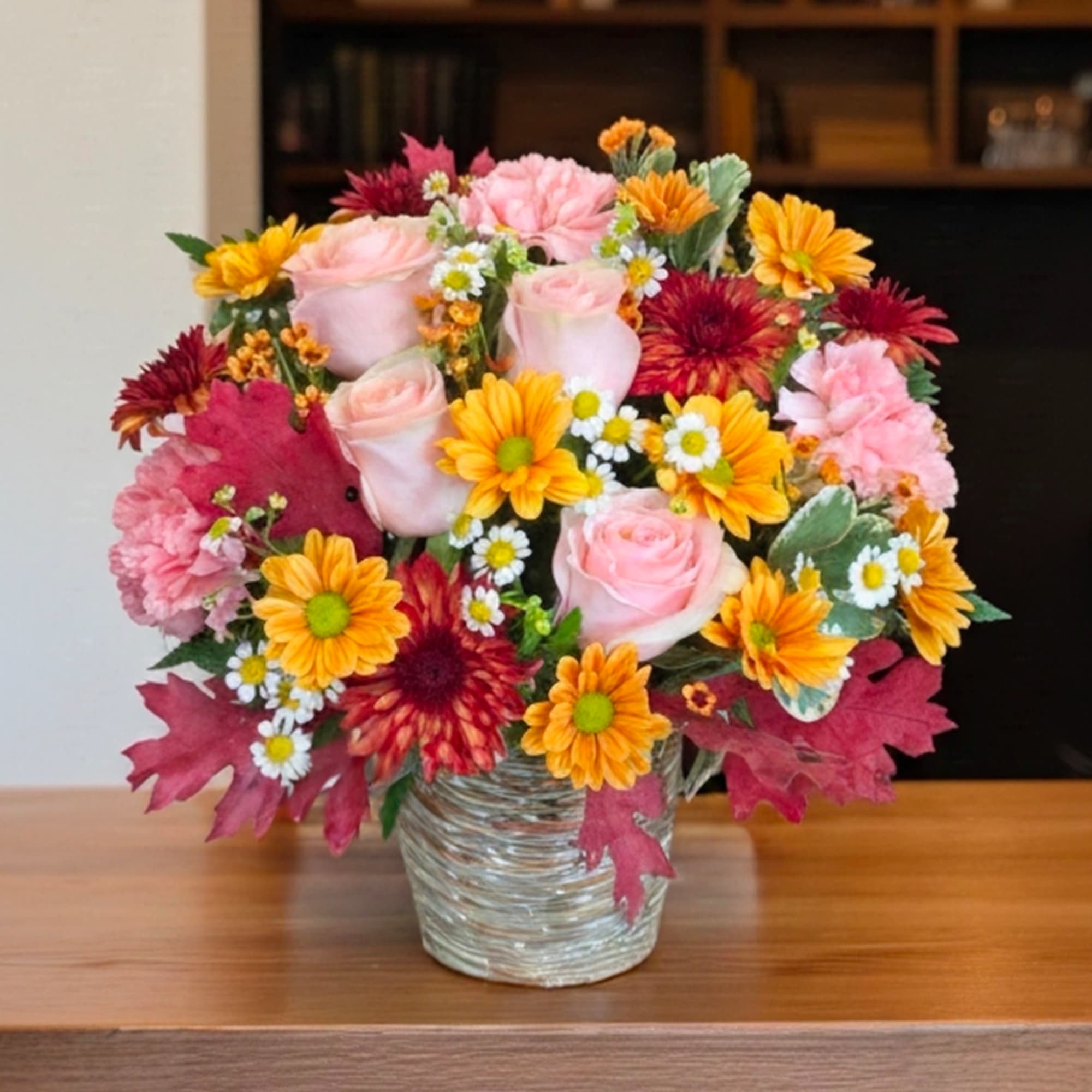 Pink roses and orange daisies in a clear glass vase