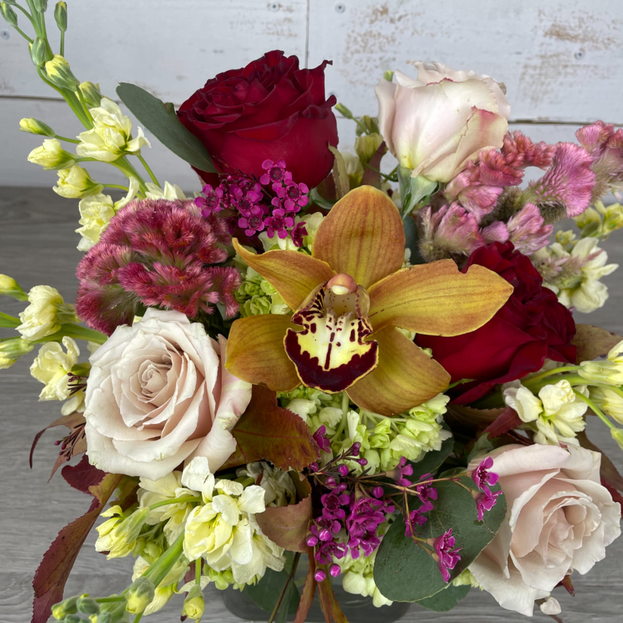 Bouquet of red and blush roses with a yellow orchid and pink accents