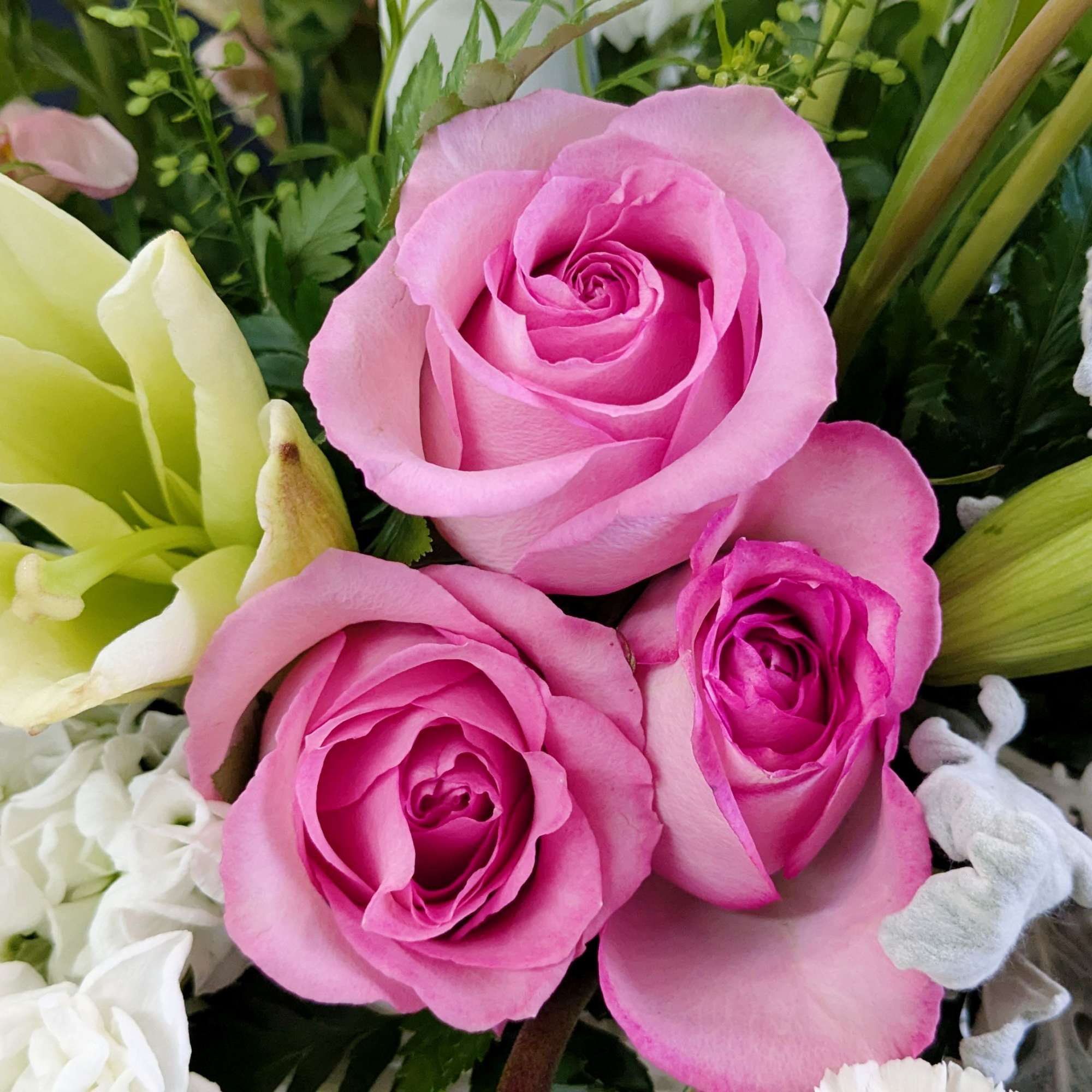 Pink roses with pale lilies and white flowers in a mixed bouquet