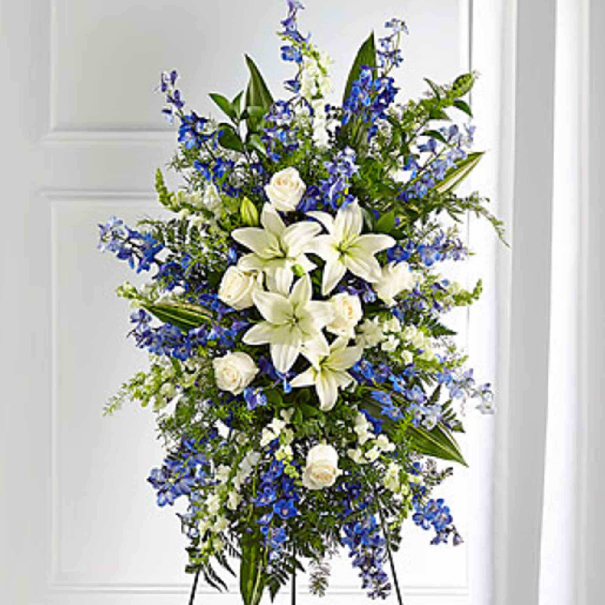 Standing floral spray with white lilies, white roses, and blue flowers