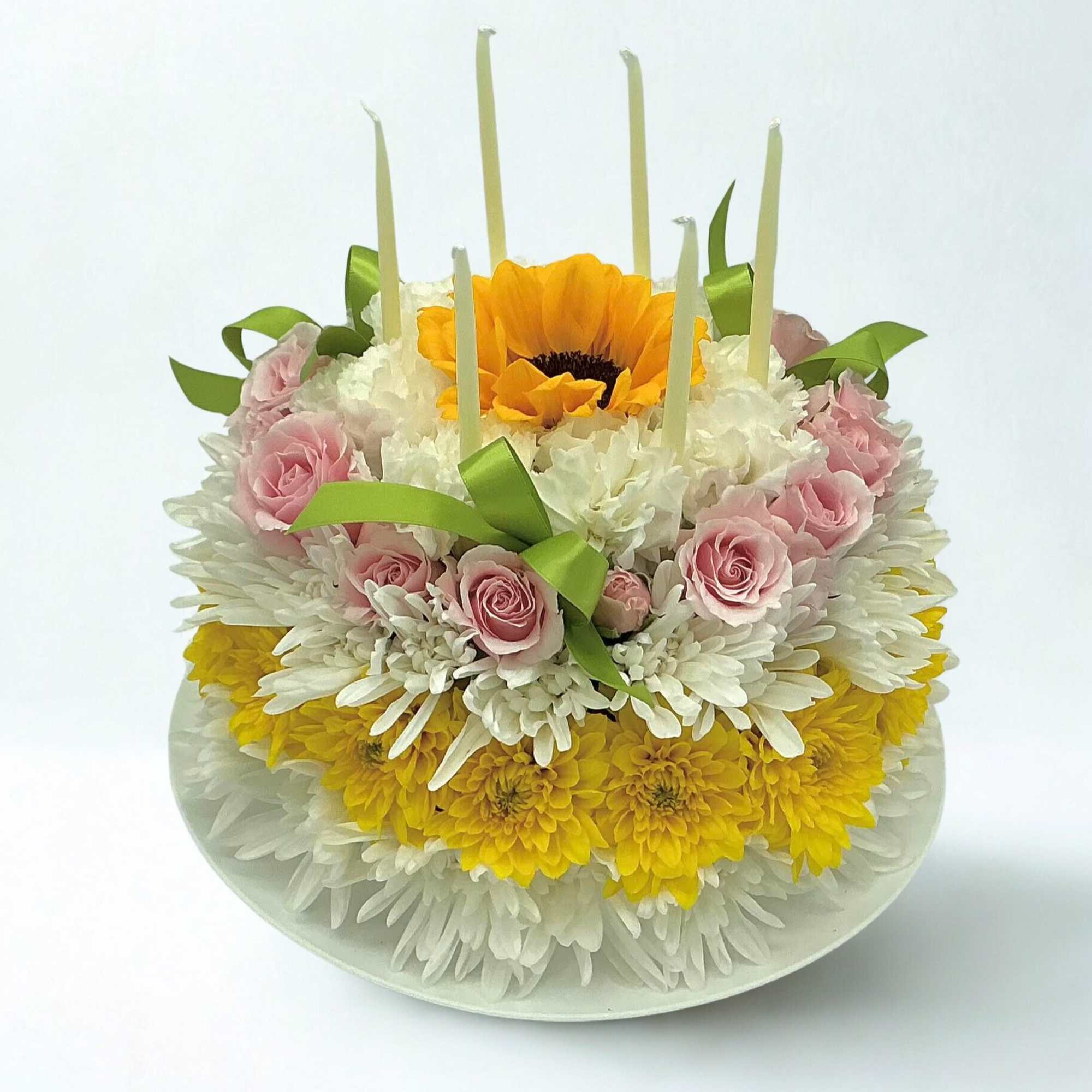 Tiered floral cake with pink roses, white and yellow chrysanthemums, and a sunflower top