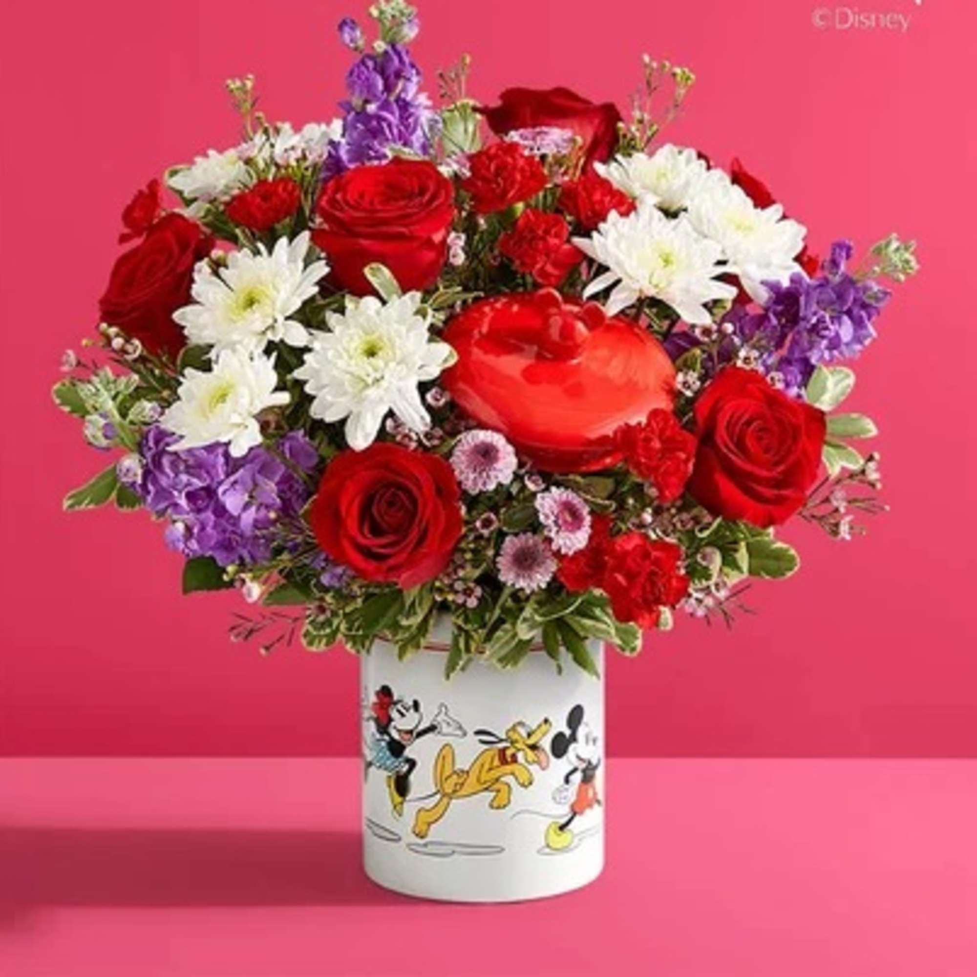 Red roses and white daisies in a Mickey Mouse vase