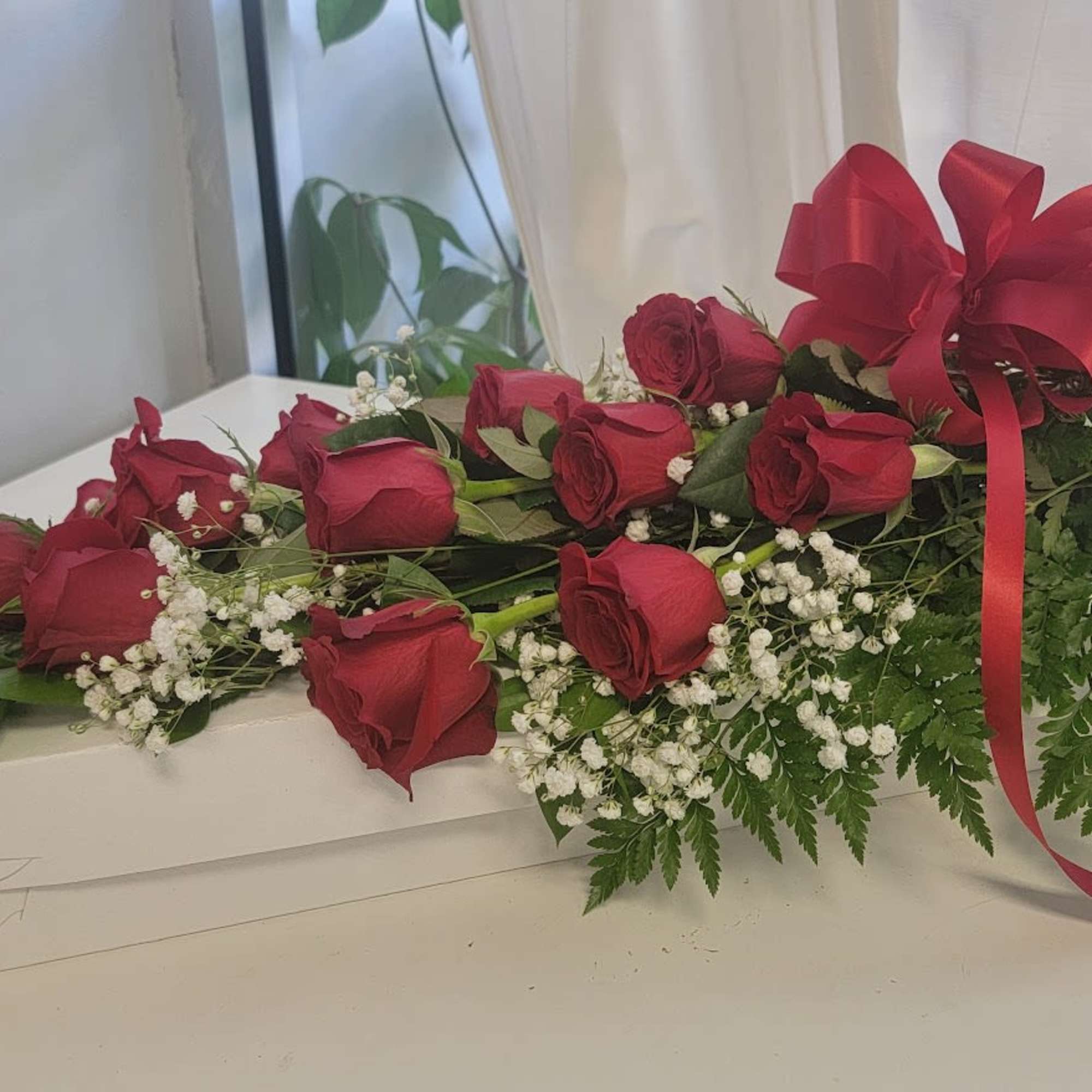 Long-stem red roses with baby's breath and a red ribbon on a white box