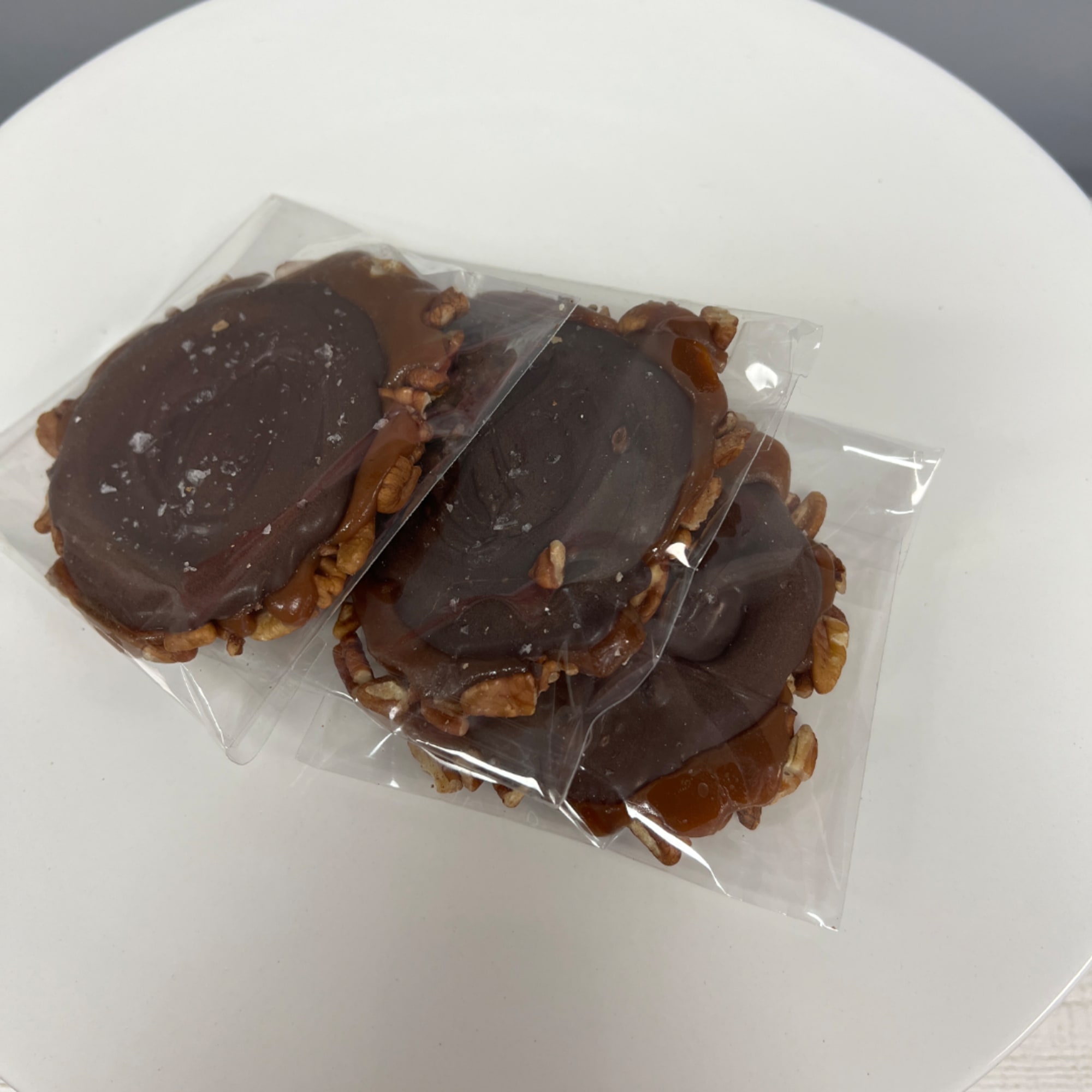 Three chocolate-covered treats in clear plastic wrappers on a white plate