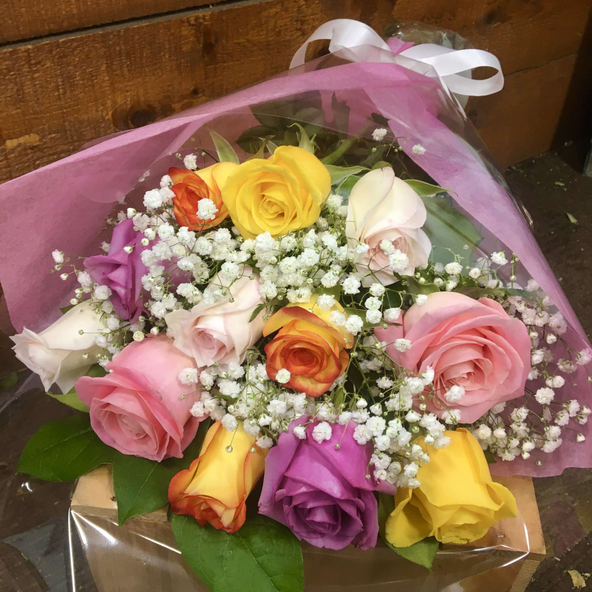 Bouquet of multicolored roses with baby's breath in pink wrap