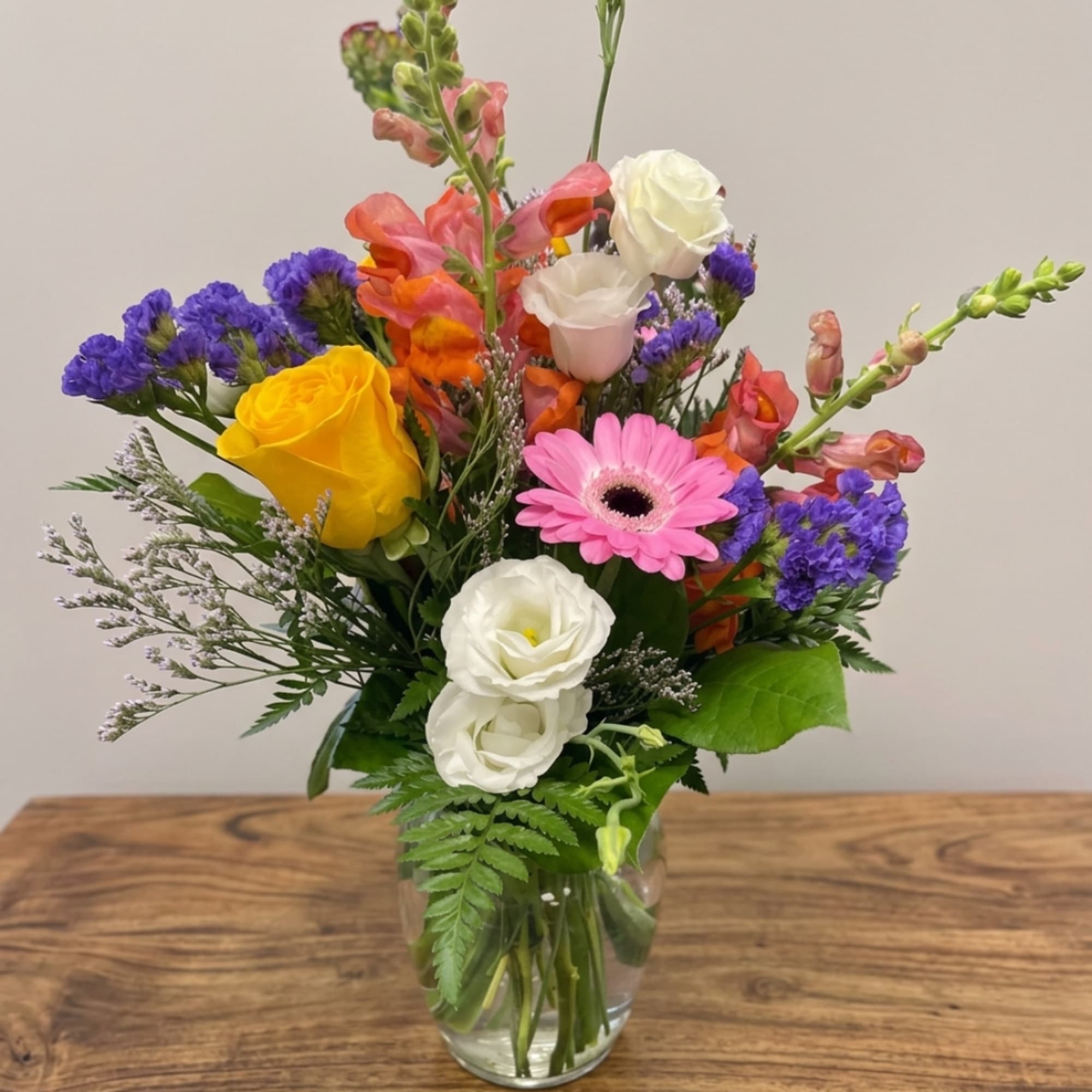 Colorful mixed bouquet in a clear glass vase with roses, gerbera daisy, and snapdragons, photo 3 of 9