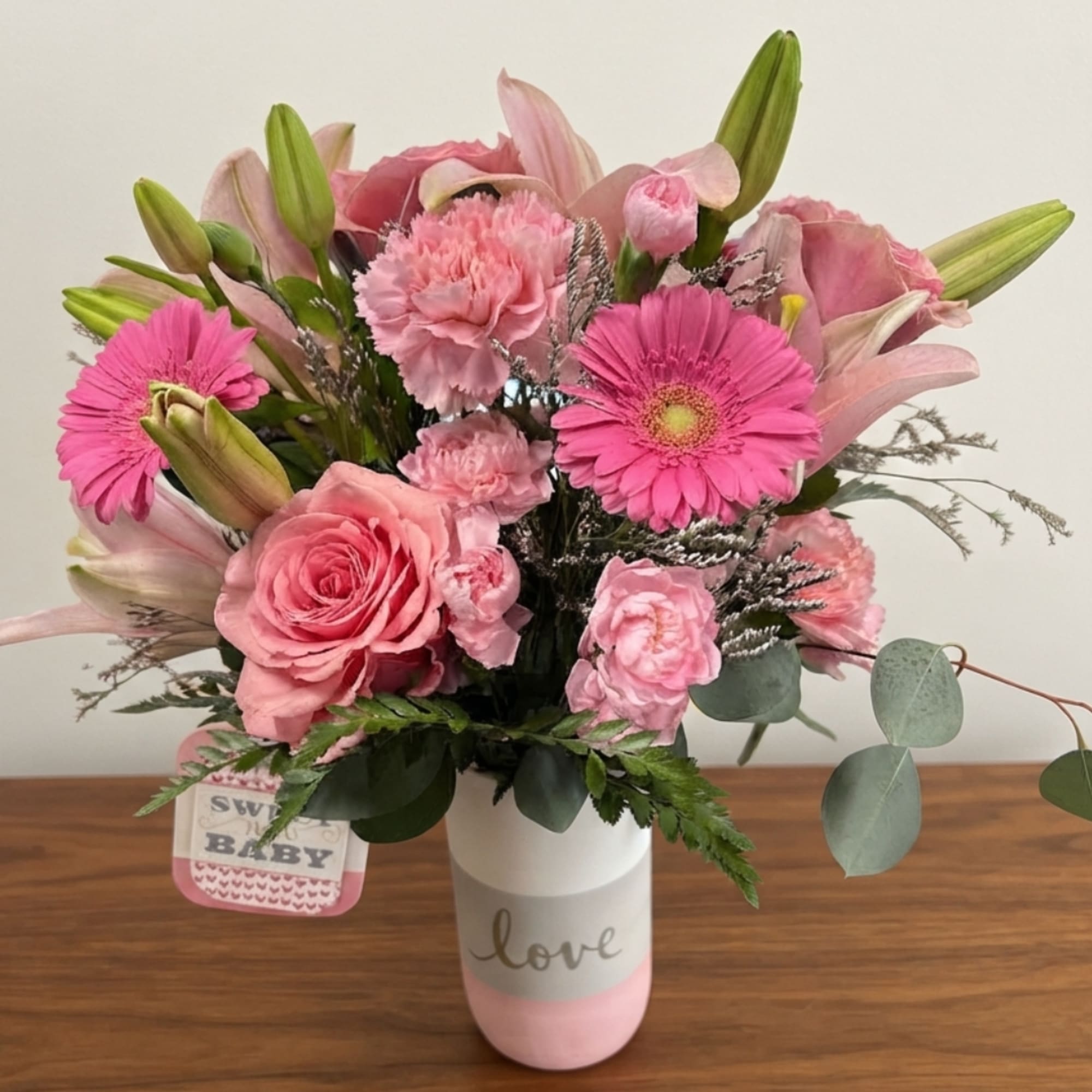 Pink mixed bouquet in a white and pink vase with a "love" label