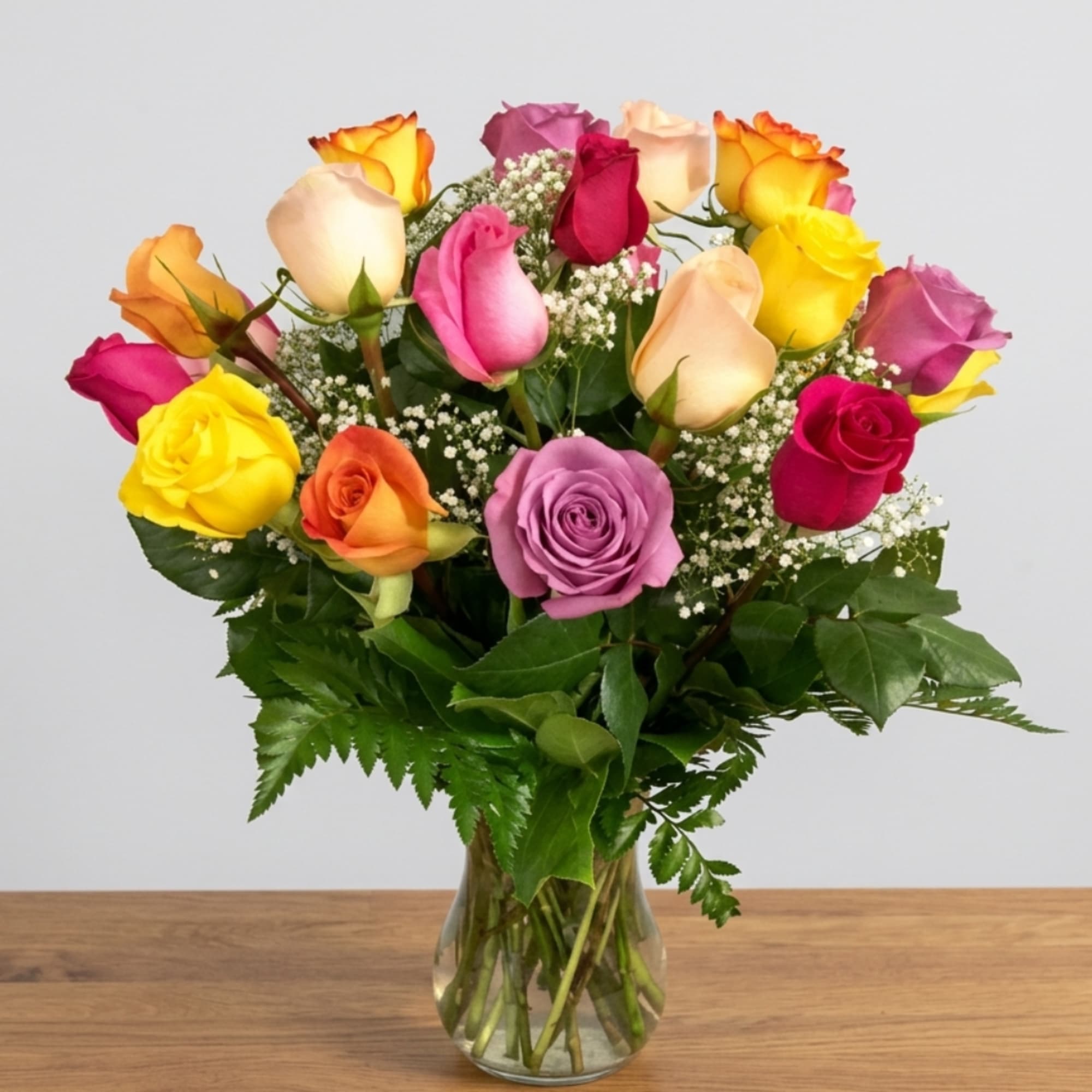 Mixed roses in a clear glass vase with baby's breath