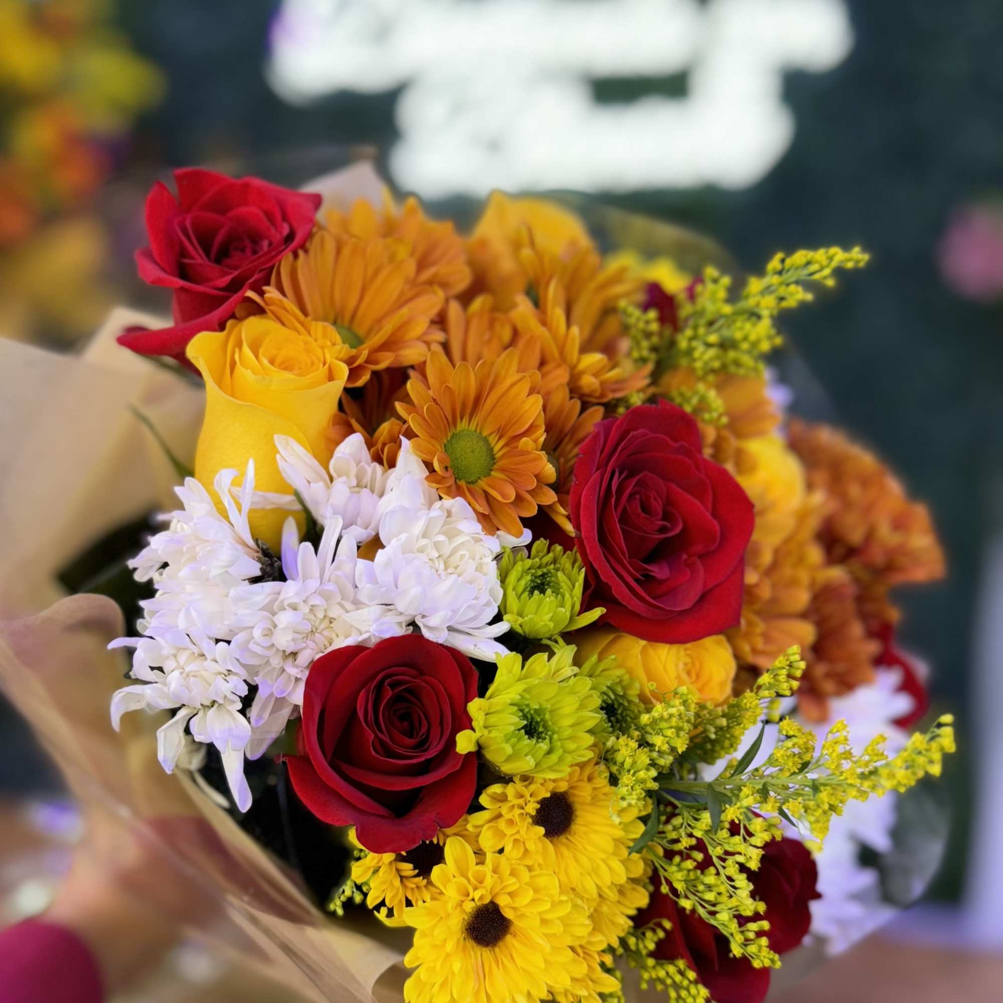"A stunning blend of red, yellow roses and daisies in autumn hues