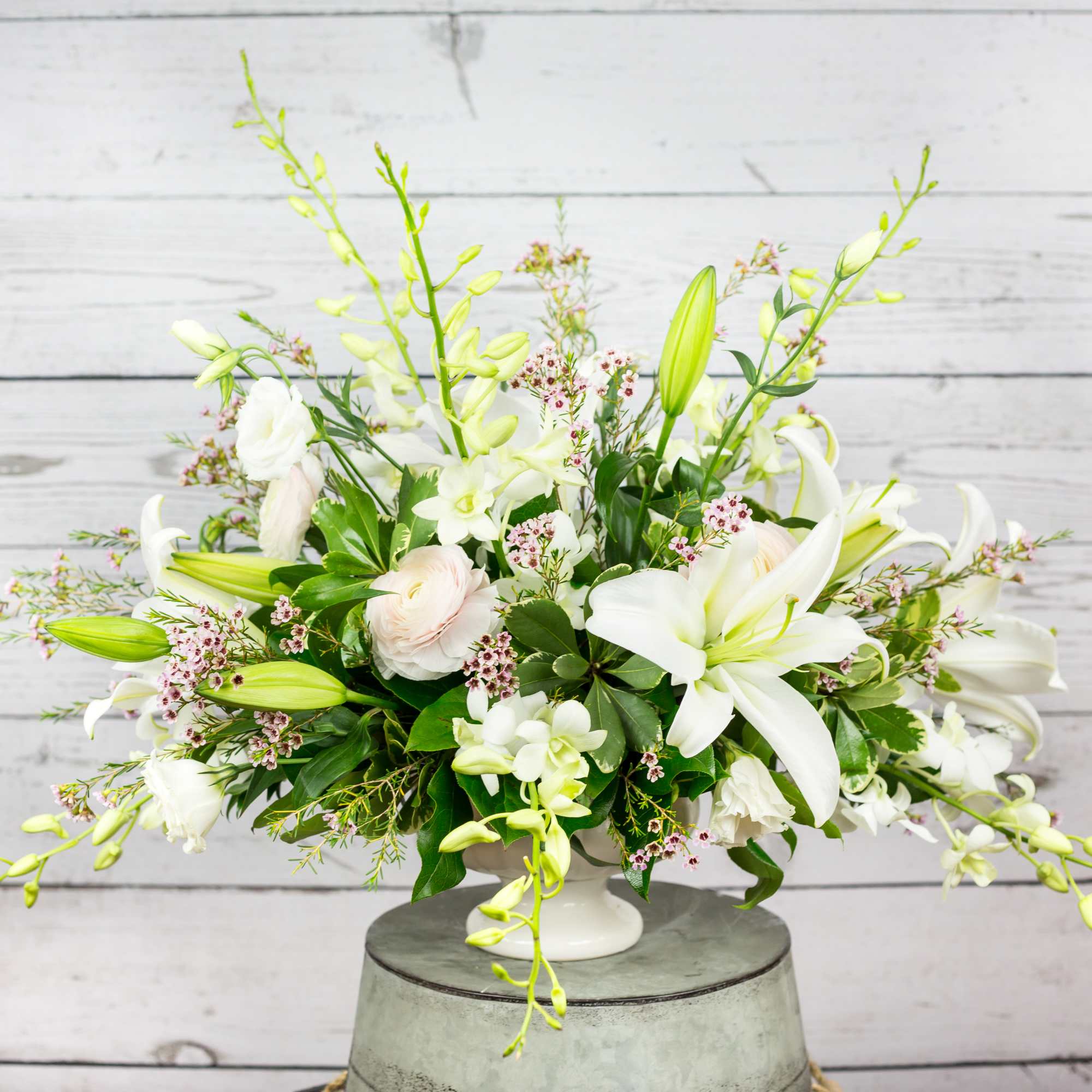 White lilies and pale blooms arranged in a low white vase