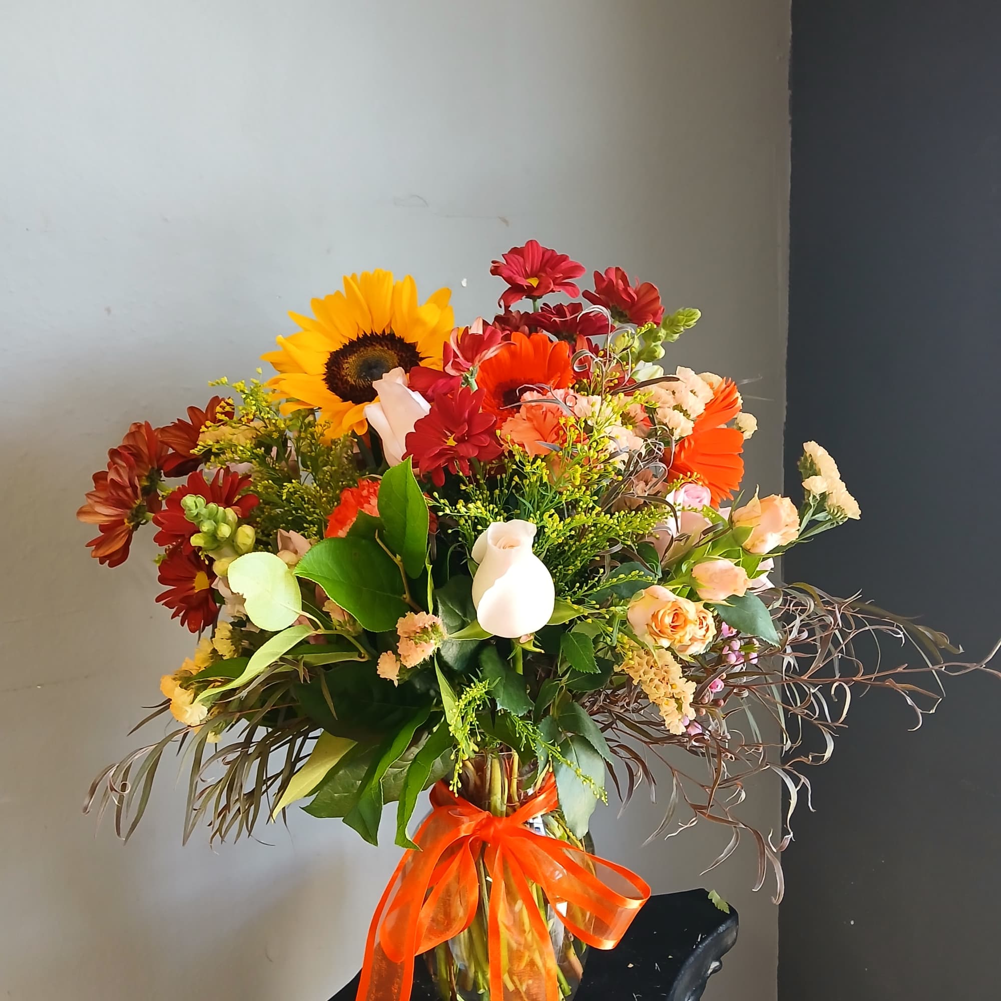 Mixed bouquet in a glass vase with a bright orange ribbon