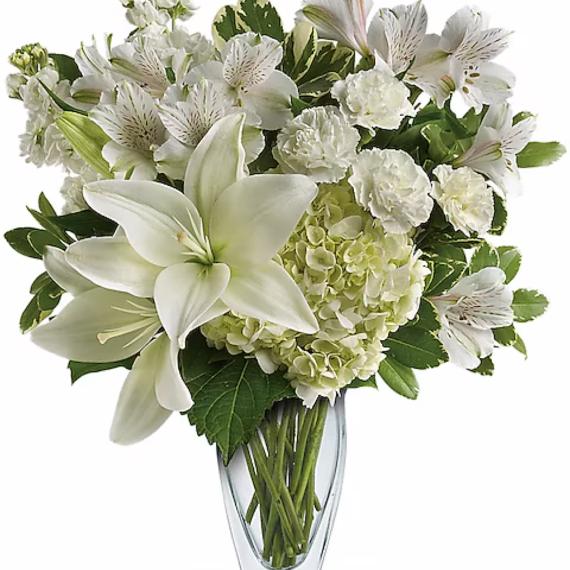 White lilies and mixed white flowers arranged in a clear glass vase
