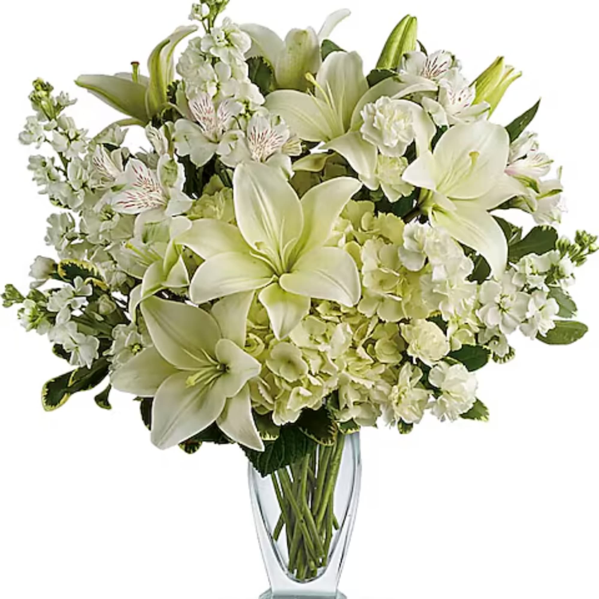 White lilies and mixed white flowers arranged in a clear glass vase