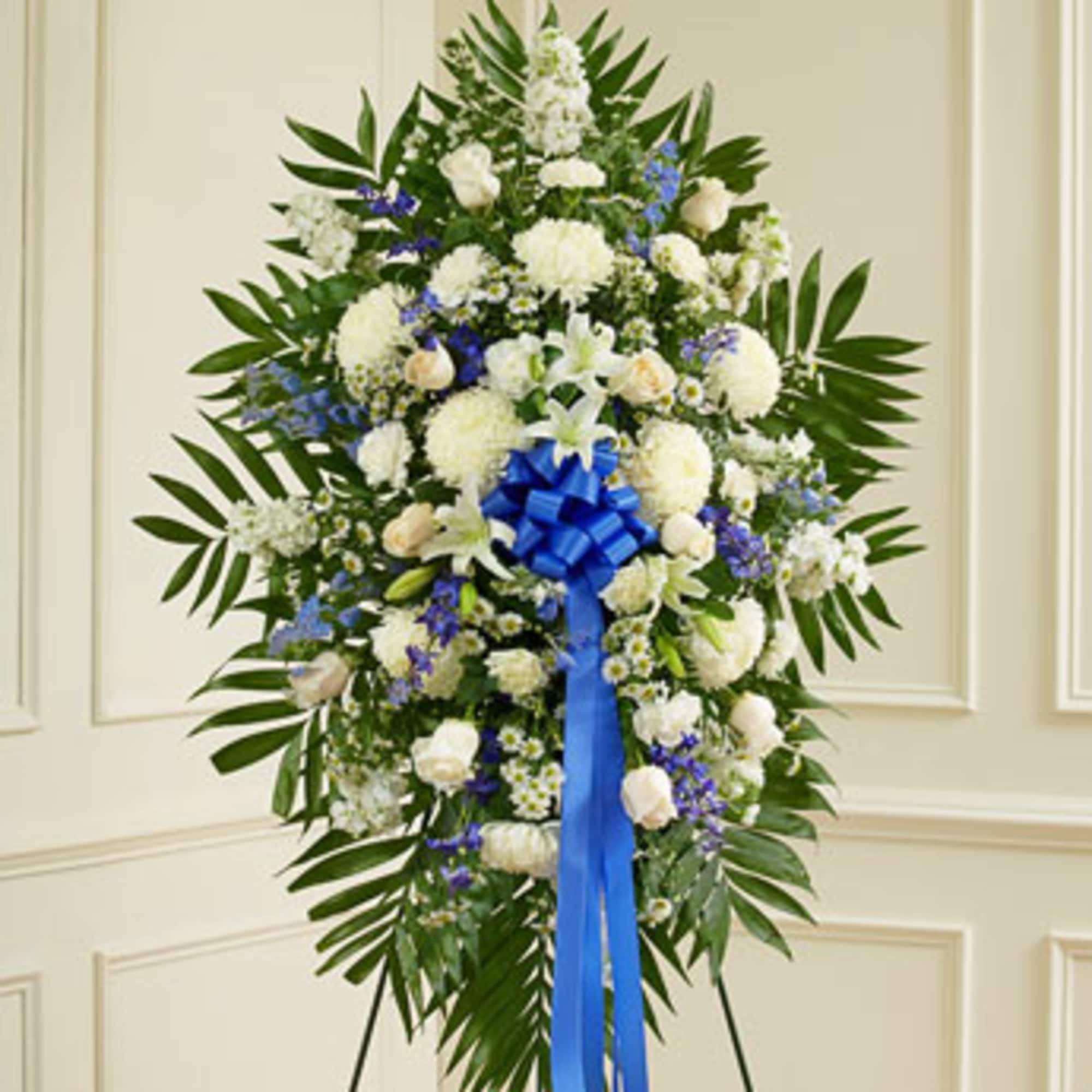 Standing floral spray of white and blue flowers with a blue ribbon